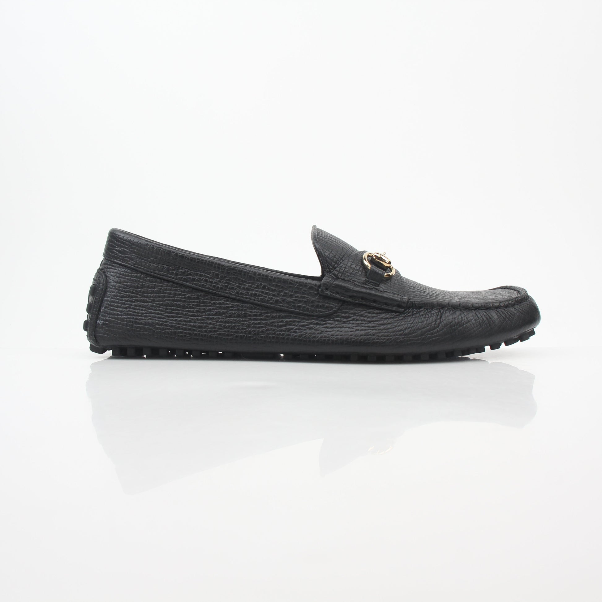 Gucci black leather Ayrton horsebit driving loafers with gold accents, stylish men's shoes on a white background.