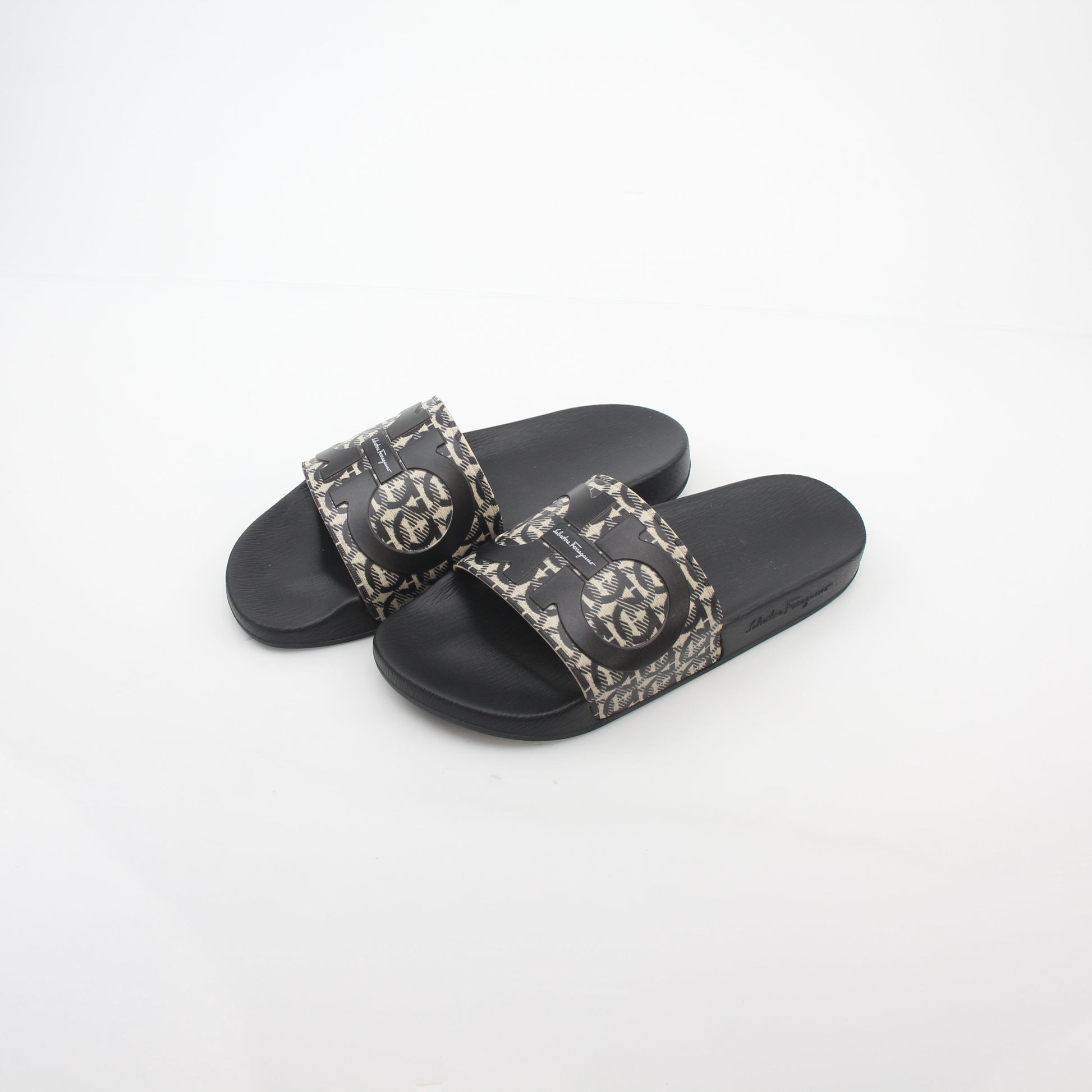 Salvatore Ferragamo black and beige Groove 6 Gancini slide sandals with open toe and strap design, worn on feet.