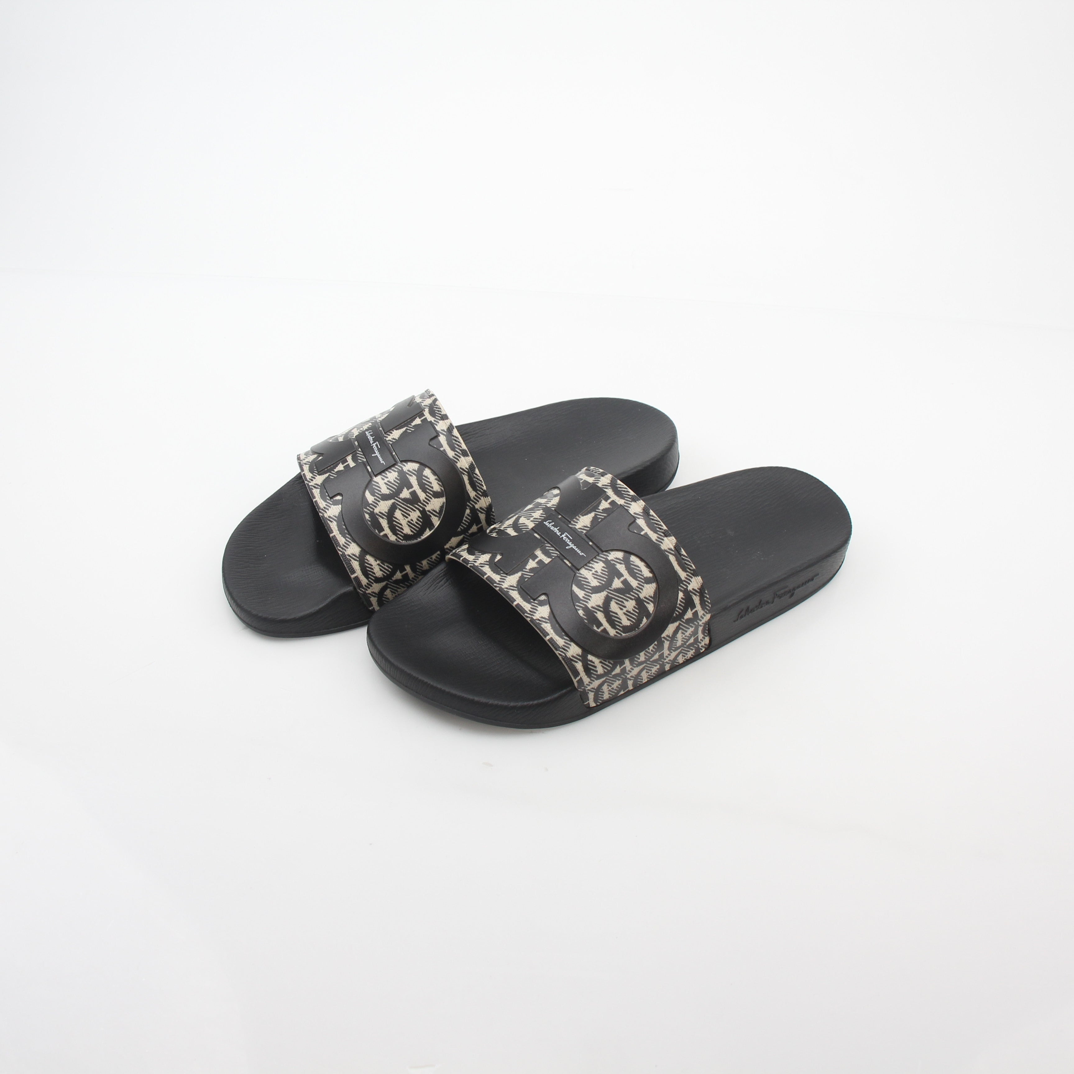 Salvatore Ferragamo black and beige Groove 6 Gancini slide sandals with open toe and strap design, worn on feet.