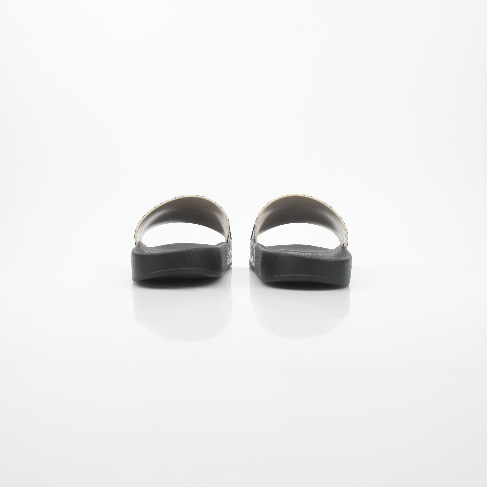 Black and beige Salvatore Ferragamo Groove 6 Gancini slide sandals with Gancini buckle design, displayed on a neutral background.