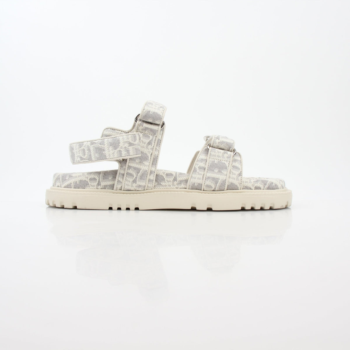 White and gray Christian Dior Dioract Oblique sandals with strap design, displayed on a neutral background.