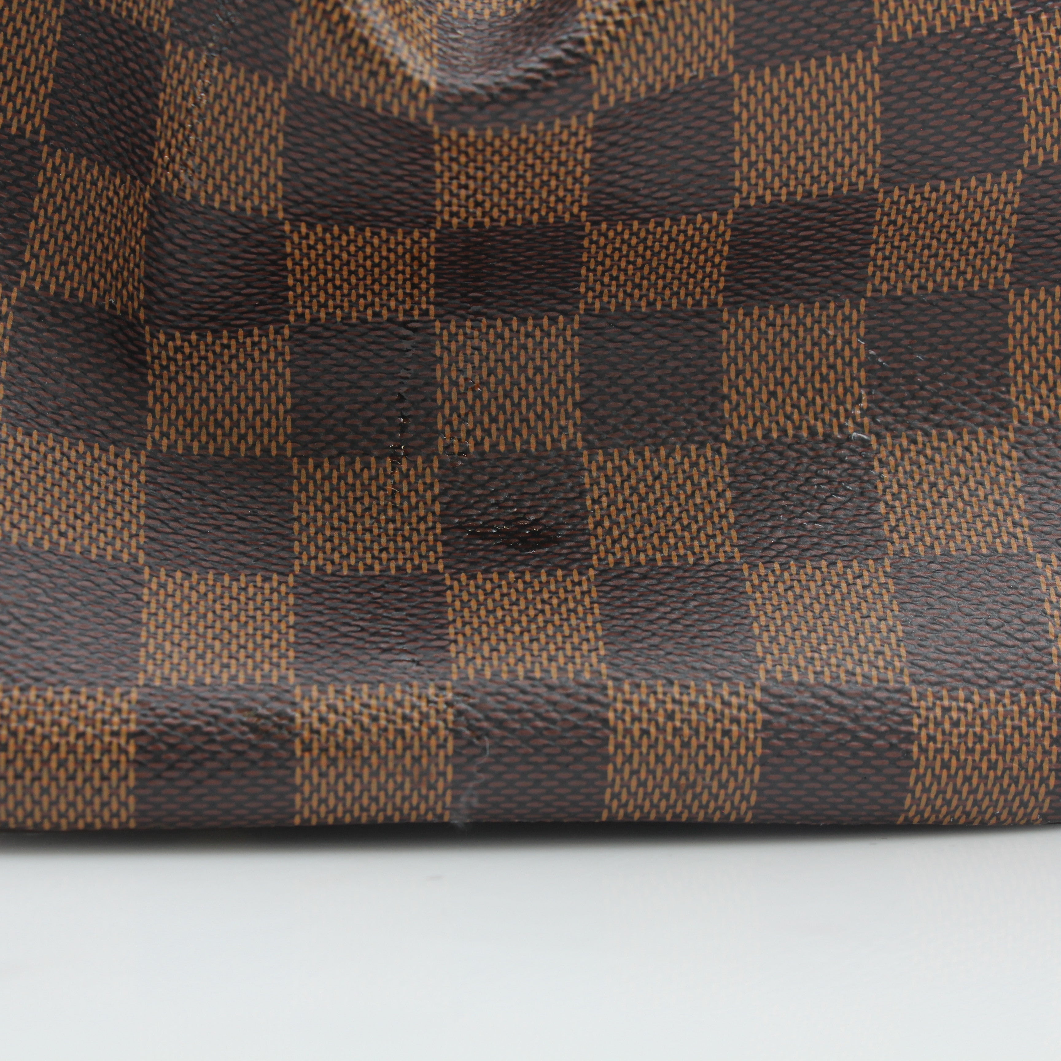 Louis Vuitton Damier Ebene Trevi GM handbag with leather handles and gold-tone hardware, showcasing the signature checkered pattern.
