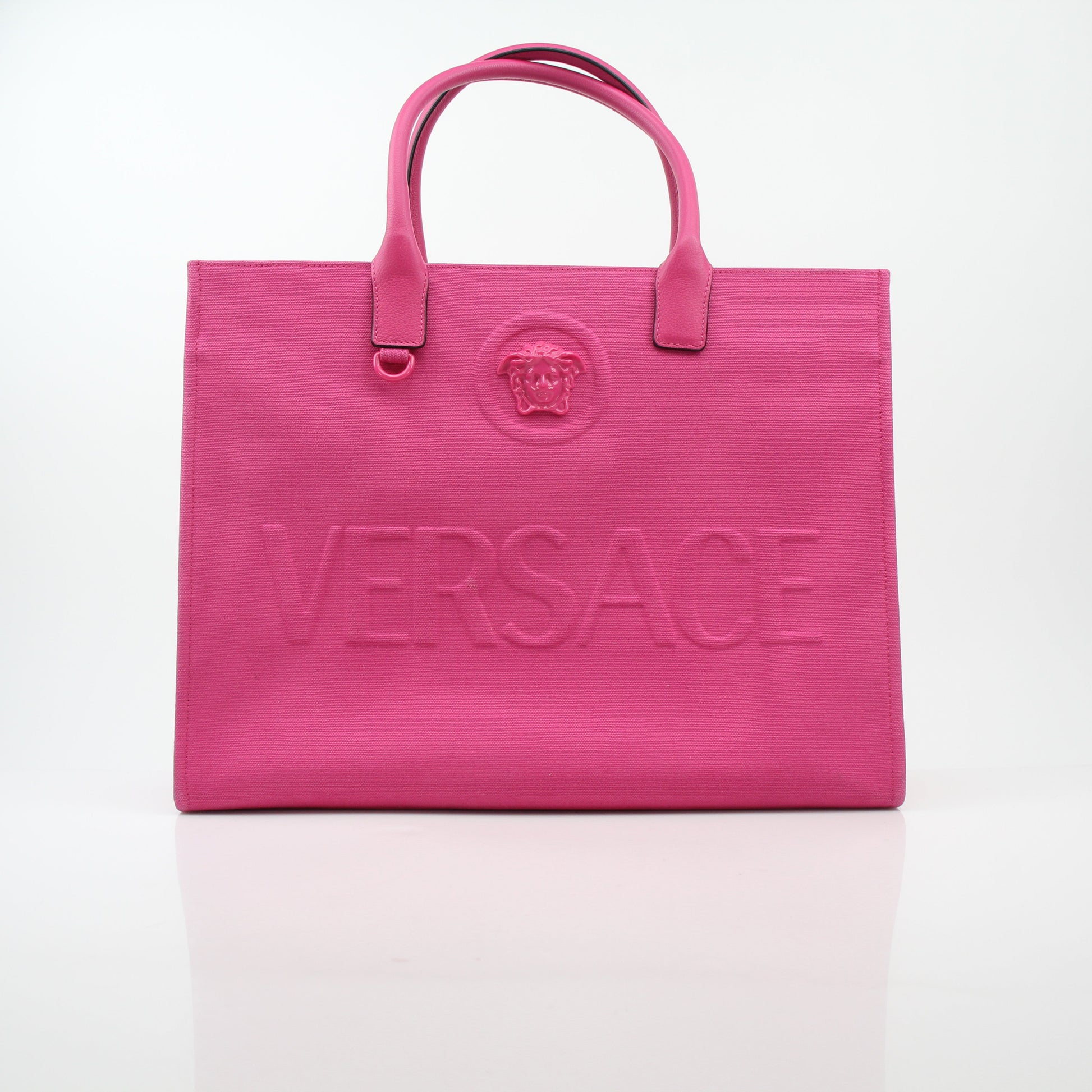 Pink Versace La Medusa embossed canvas tote bag with gold accents, large handles, and detailed Medusa logo design.