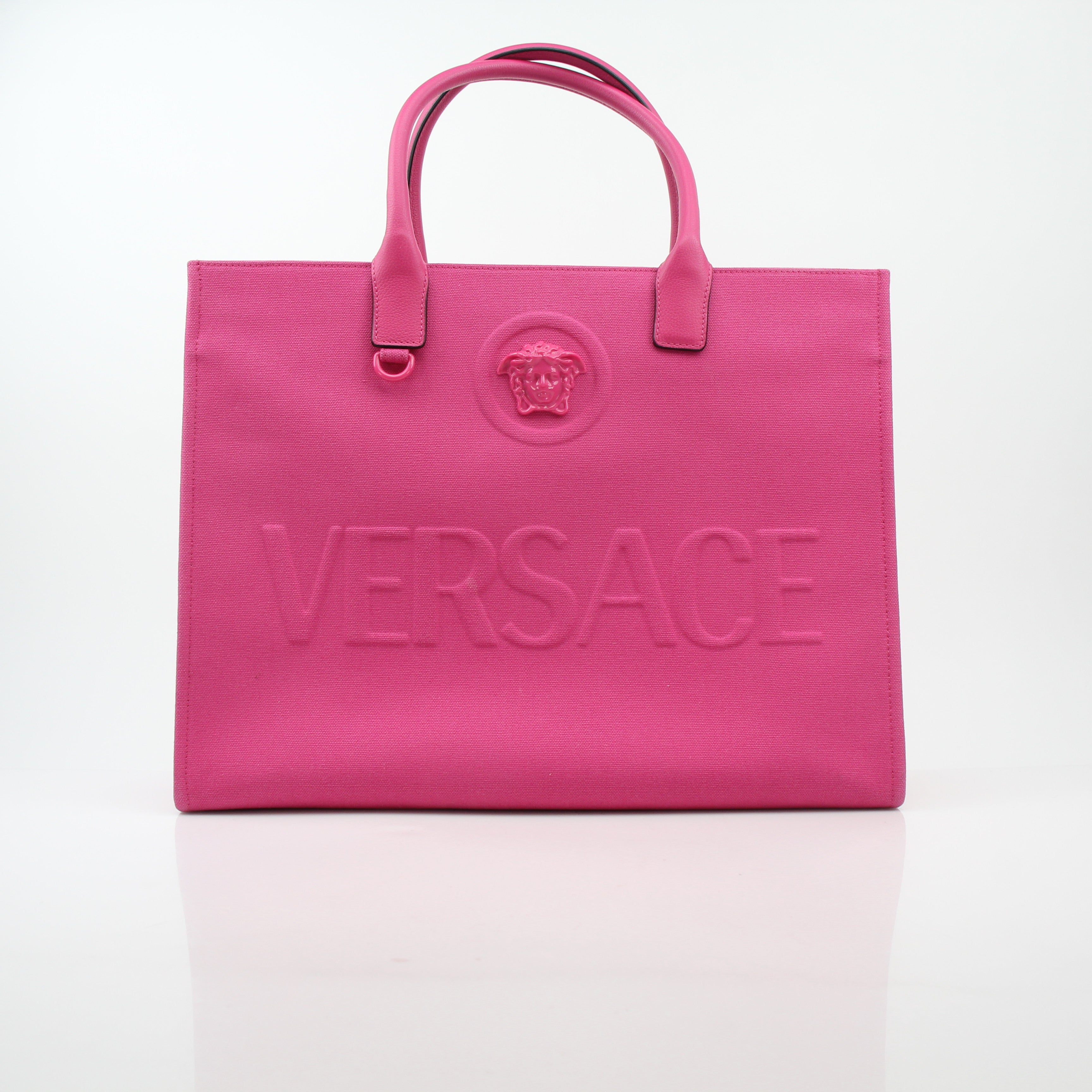 Pink Versace La Medusa embossed canvas tote bag with gold accents, large handles, and detailed Medusa logo design.