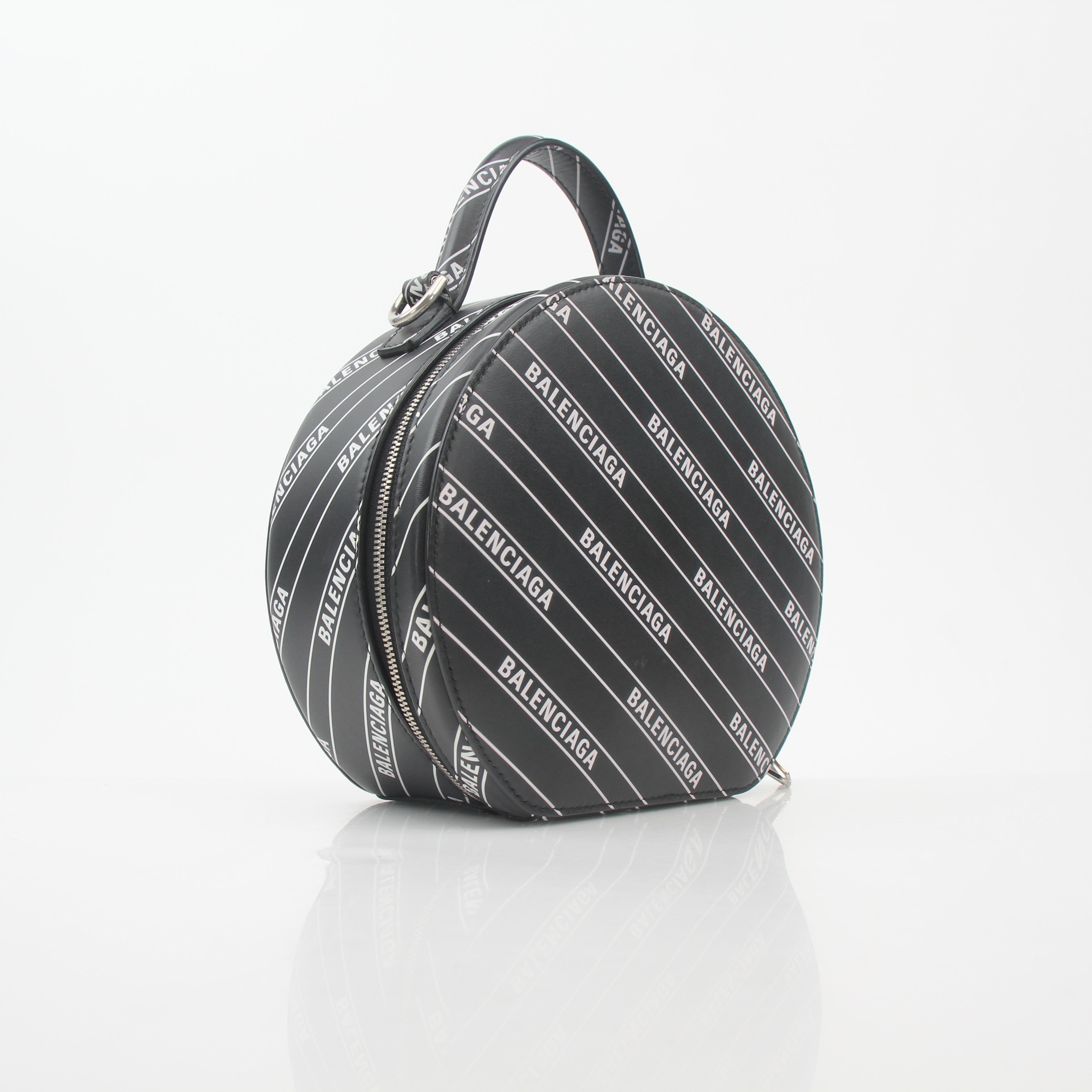 Black Balenciaga logo XS Vanity round handbag with gold accents, featuring a compact, stylish design on a white background.