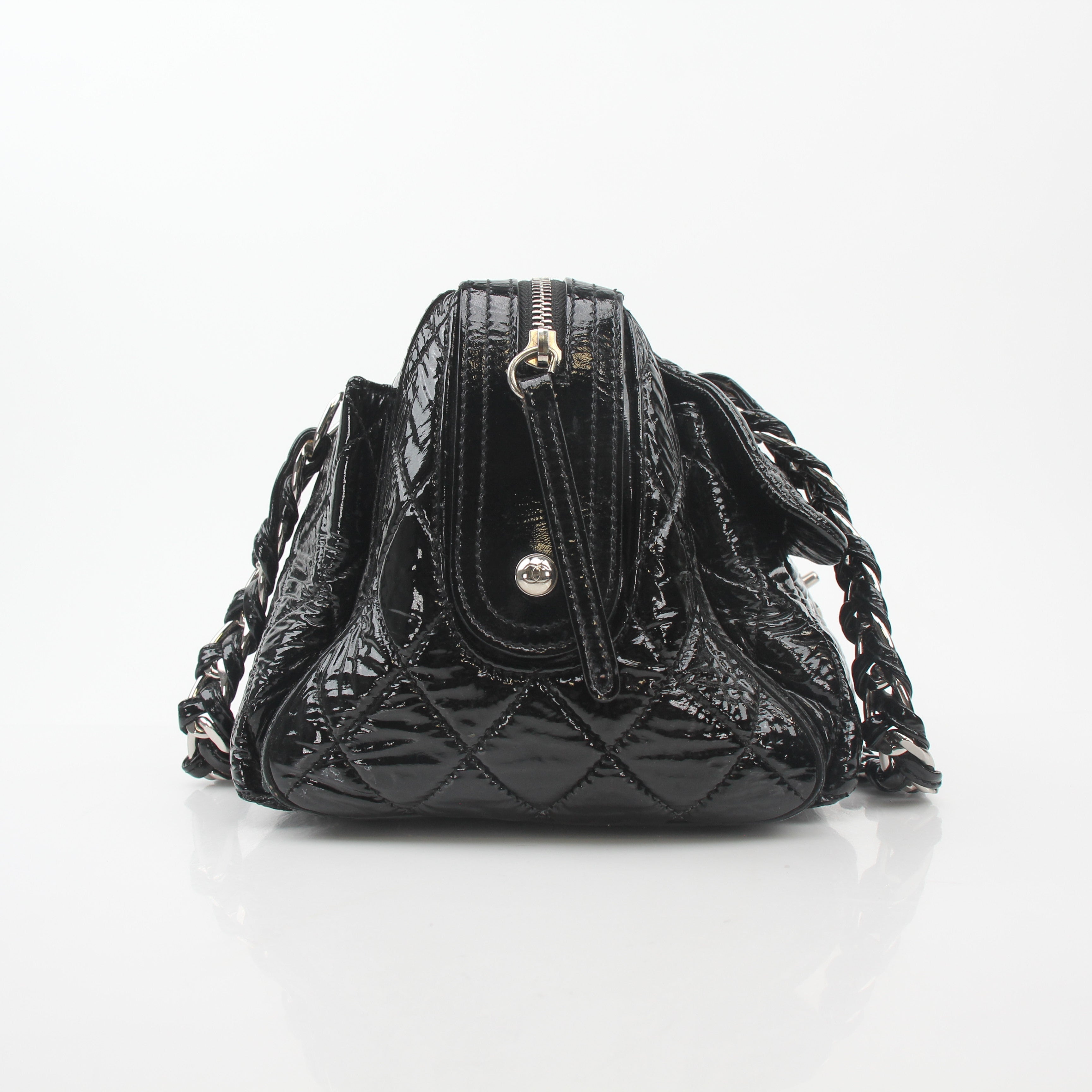 Black quilted patent Chanel handbag with glossy finish and gold hardware, featuring a flap closure and chain strap.