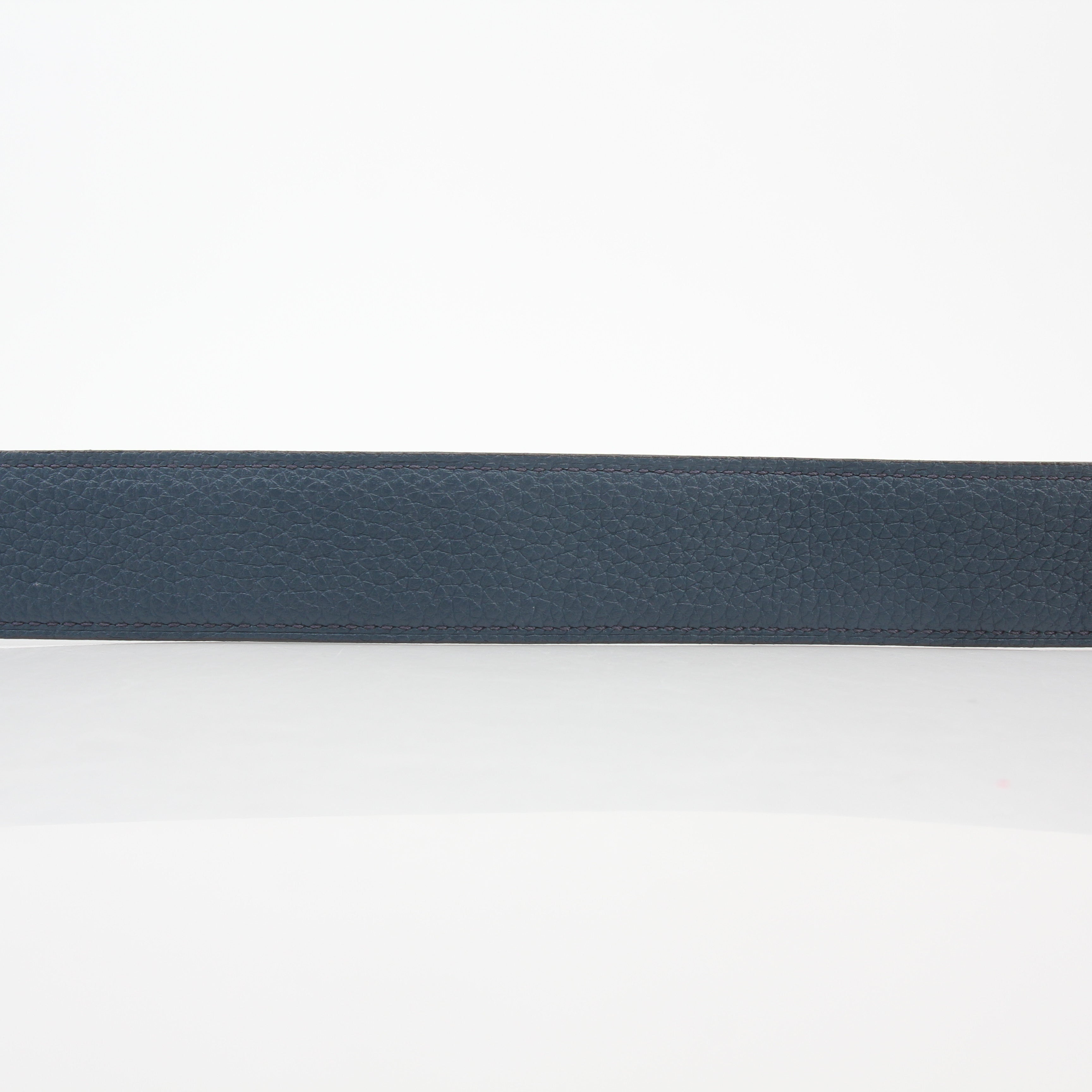 Hermès black and blue reversible belt by Gold & Beyond, showing the H buckle and reversible strap in a close-up image.