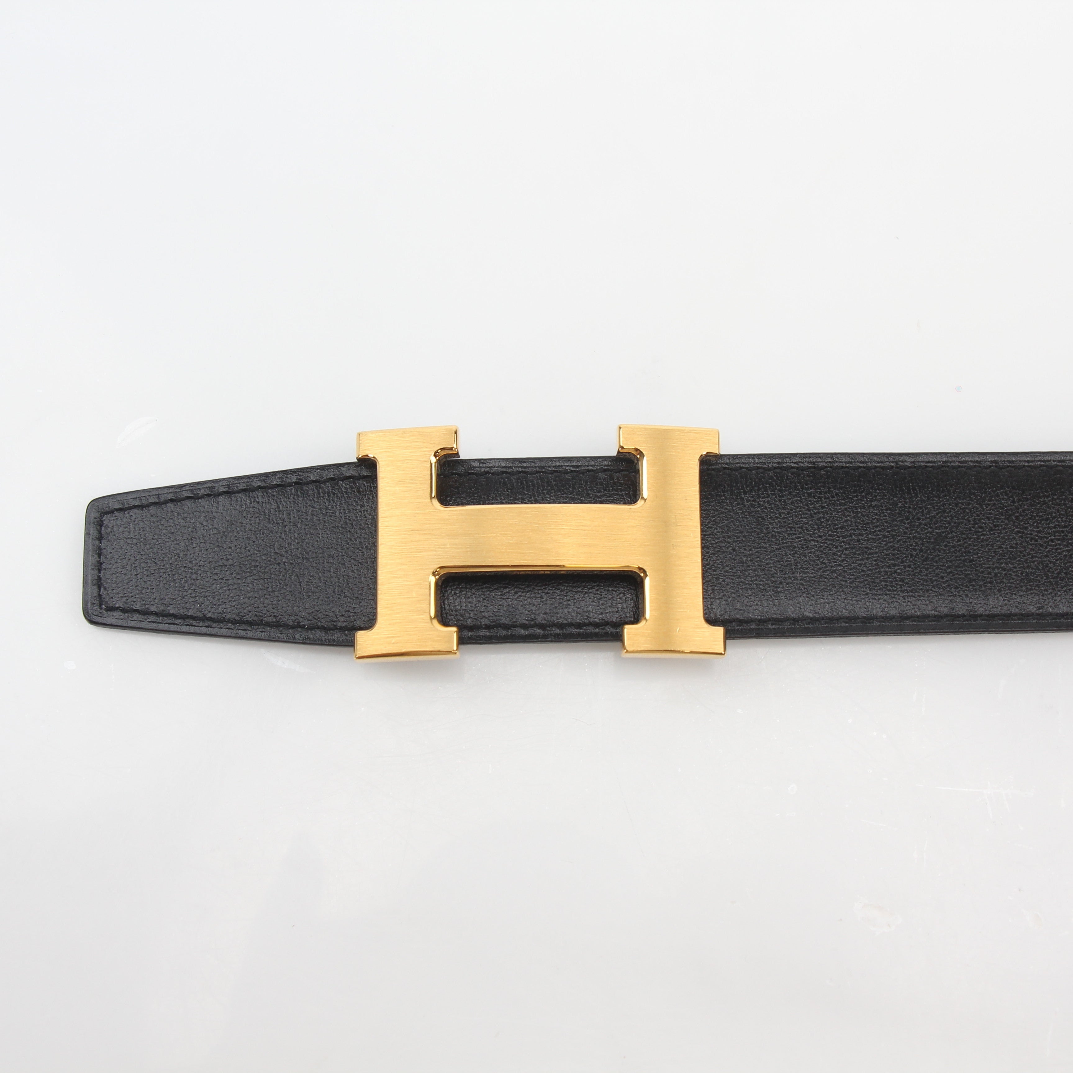 Hermès black and blue reversible belt kit with gold accents, showcasing the adjustable strap and sleek design.