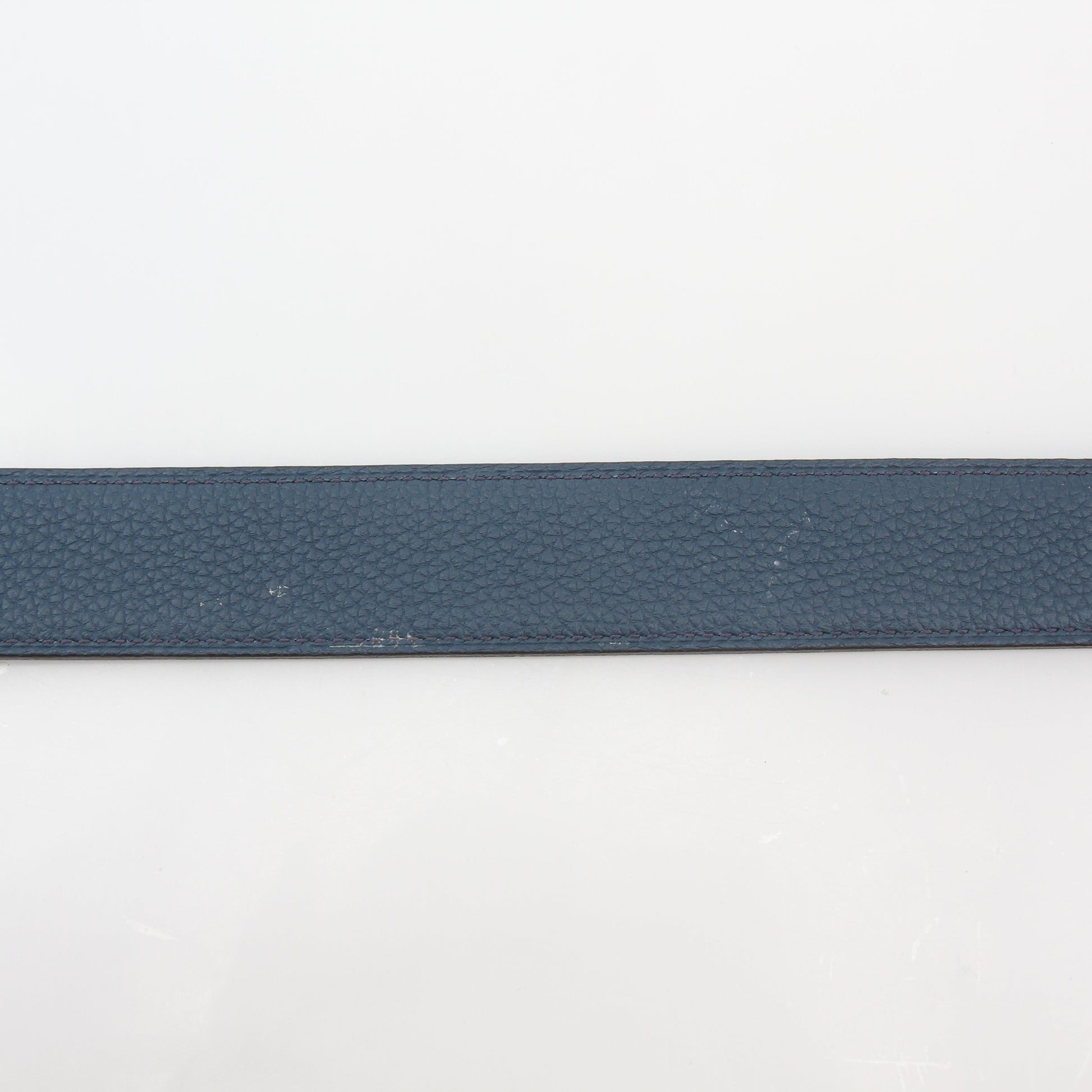 Hermès black and blue reversible belt kit with H logo, displayed with belt buckle and accessories on a neutral background.