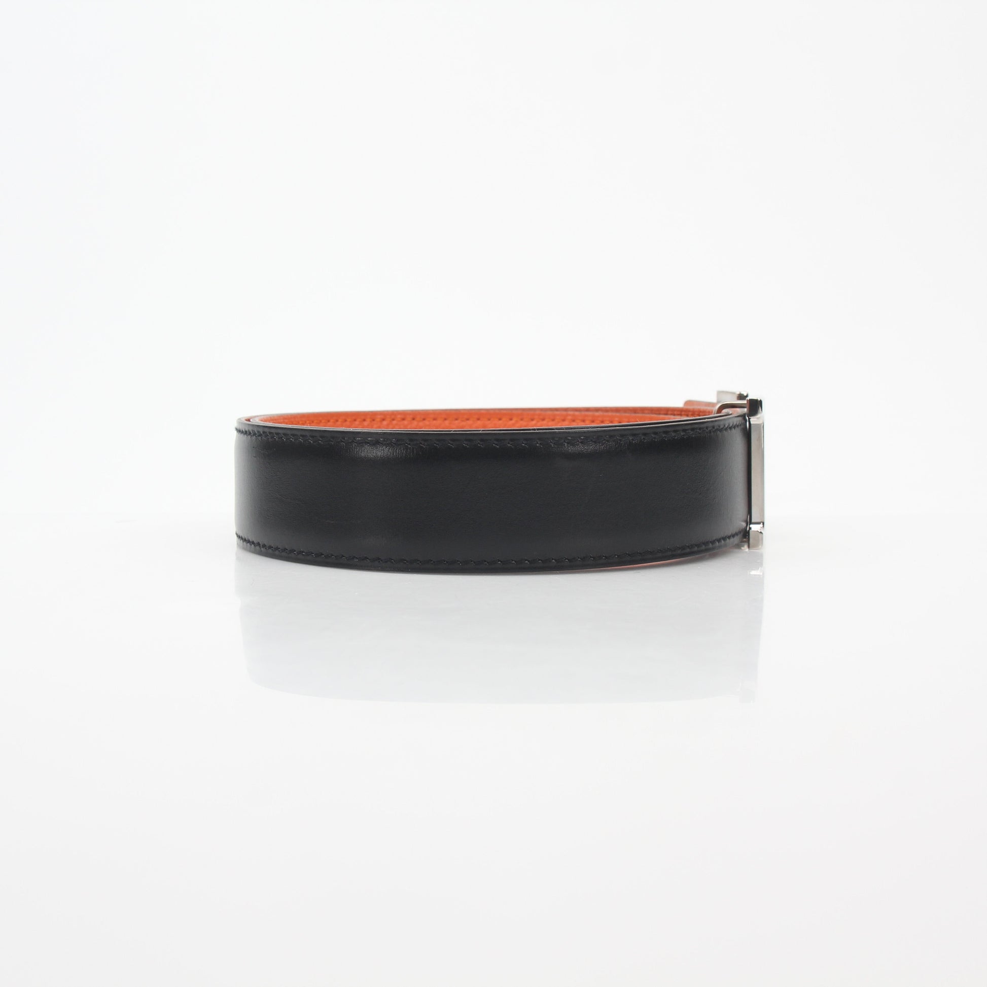 Hermès black and orange H reversible belt kit with gold hardware, displayed on a neutral background.