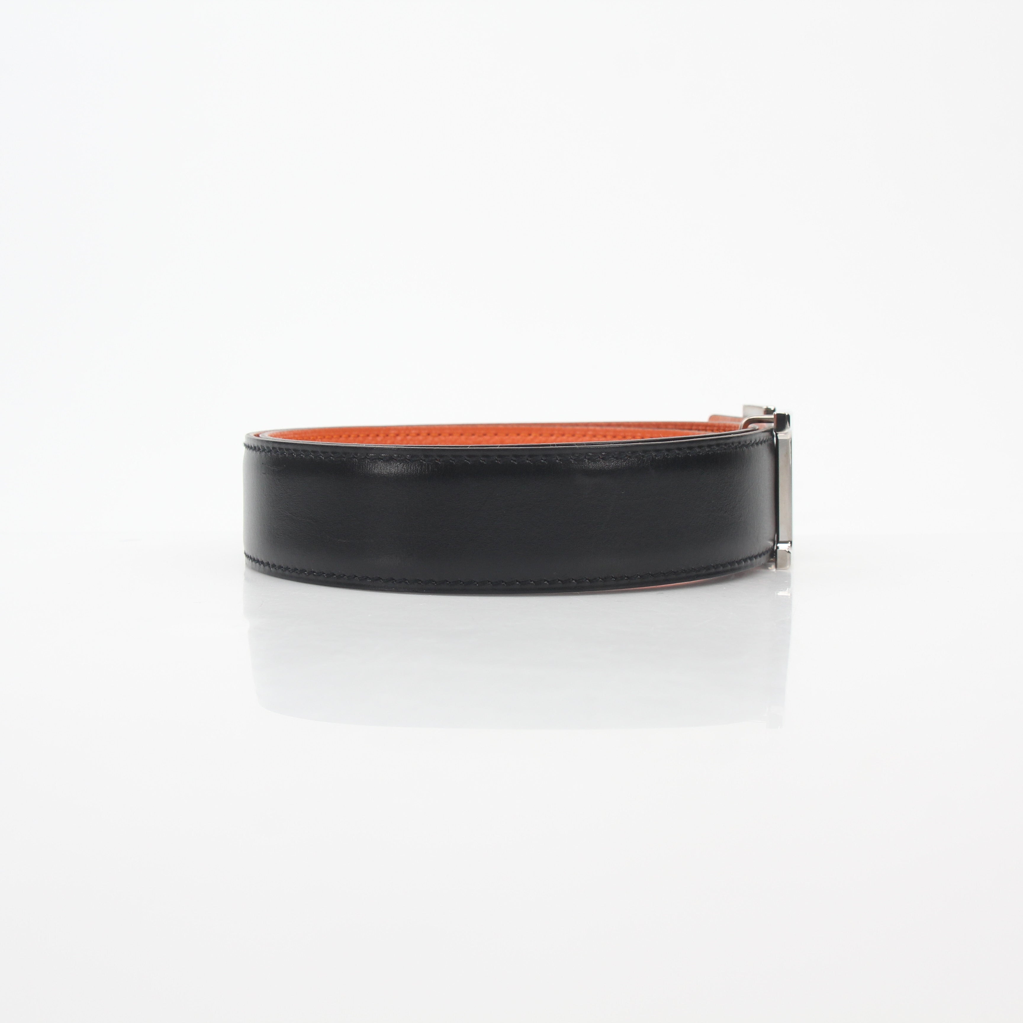 Hermès black and orange H reversible belt kit with gold hardware, displayed on a neutral background.