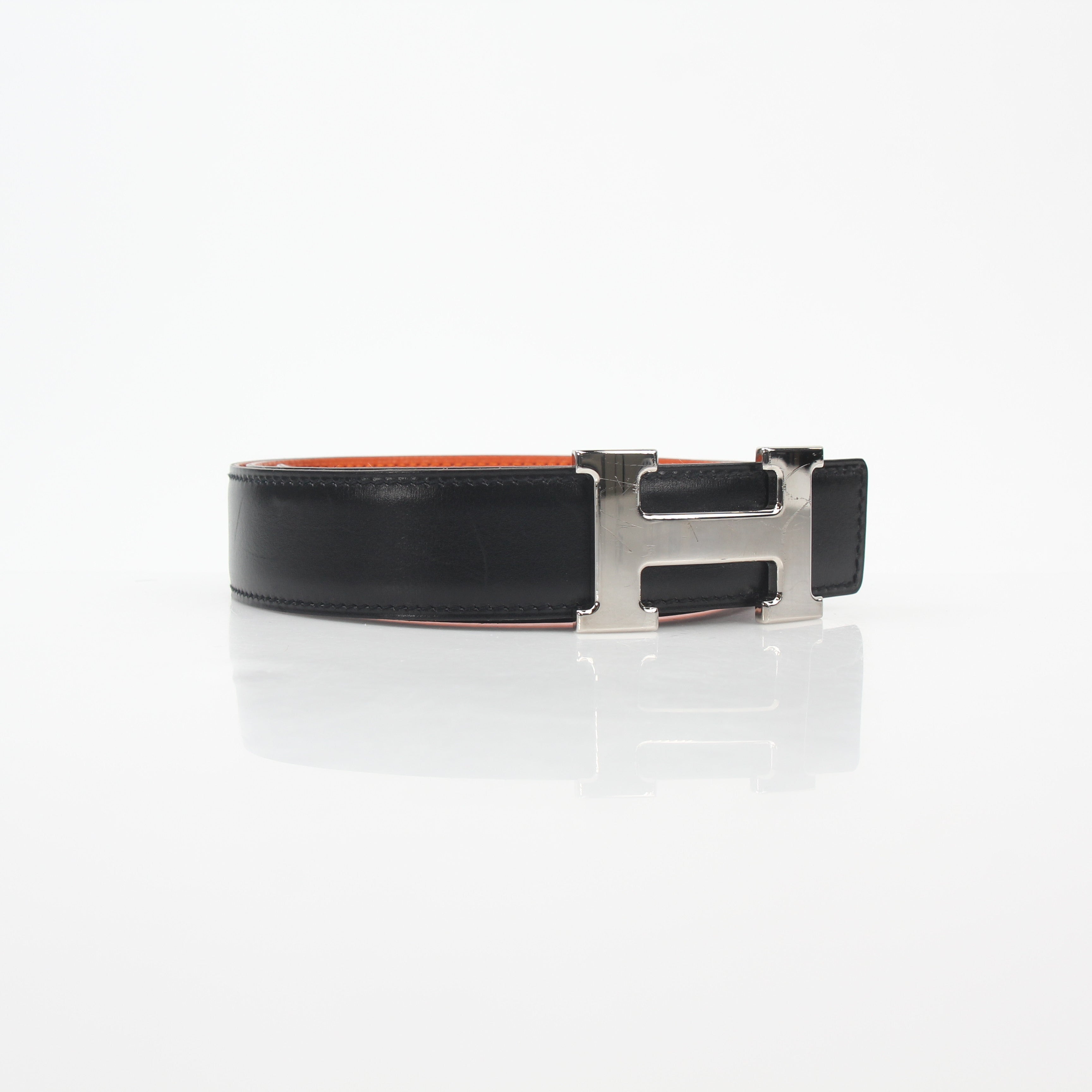 Hermès black and orange H reversible belt kit with gold accents, showcasing the stylish accessory and versatile design.