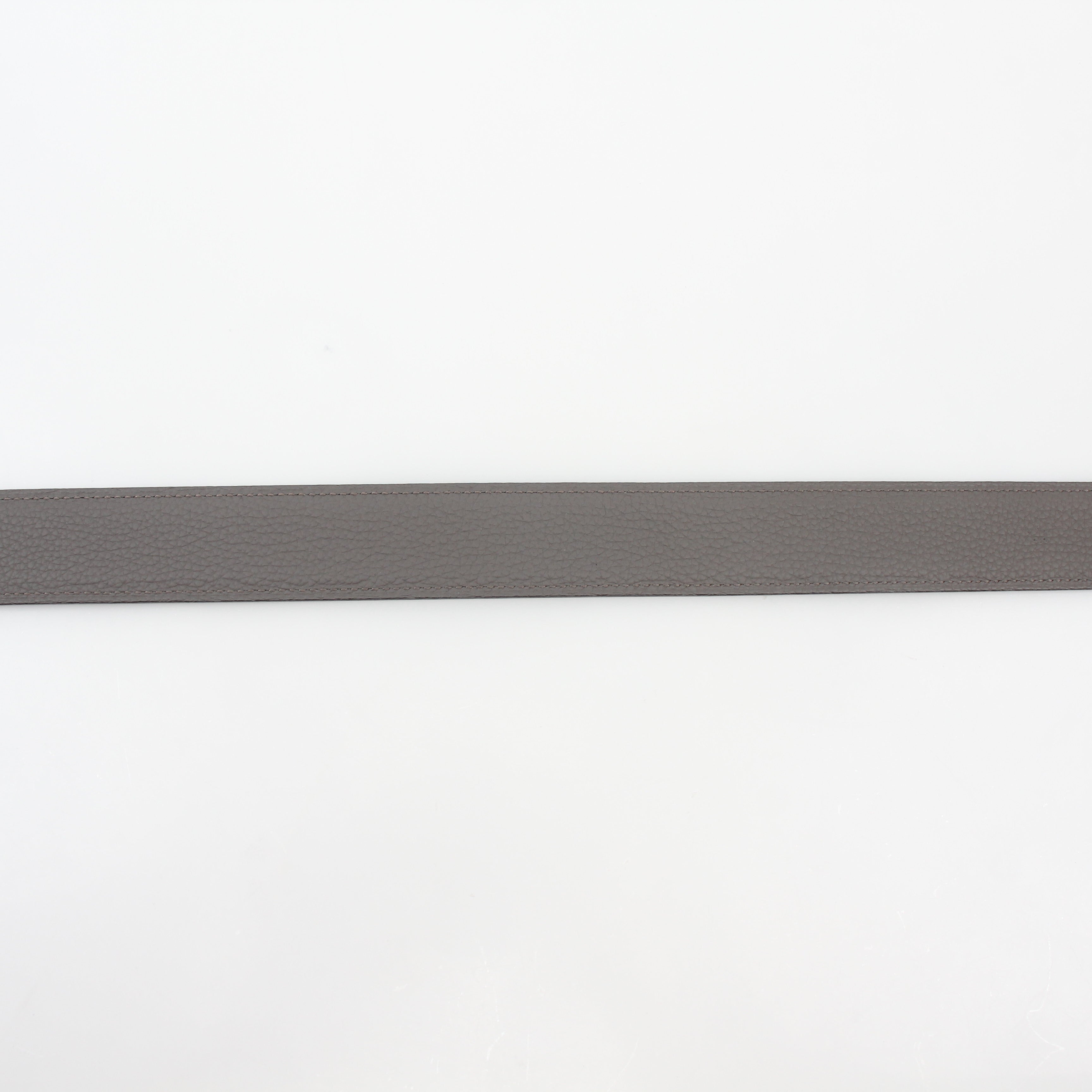 Hermès black and etoupe reversible leather belt strap with gold hardware, designed for accessories and versatile styling.