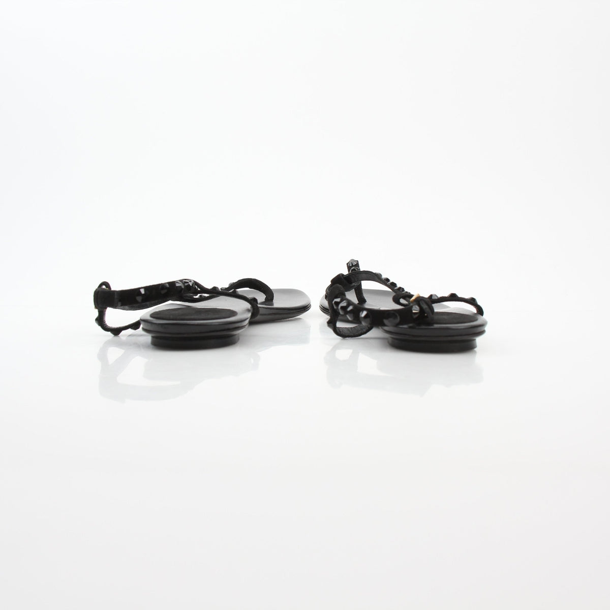 Gucci black crystal-embellished T-strap flat sandals with open toes and ankle straps, displayed on a neutral background.