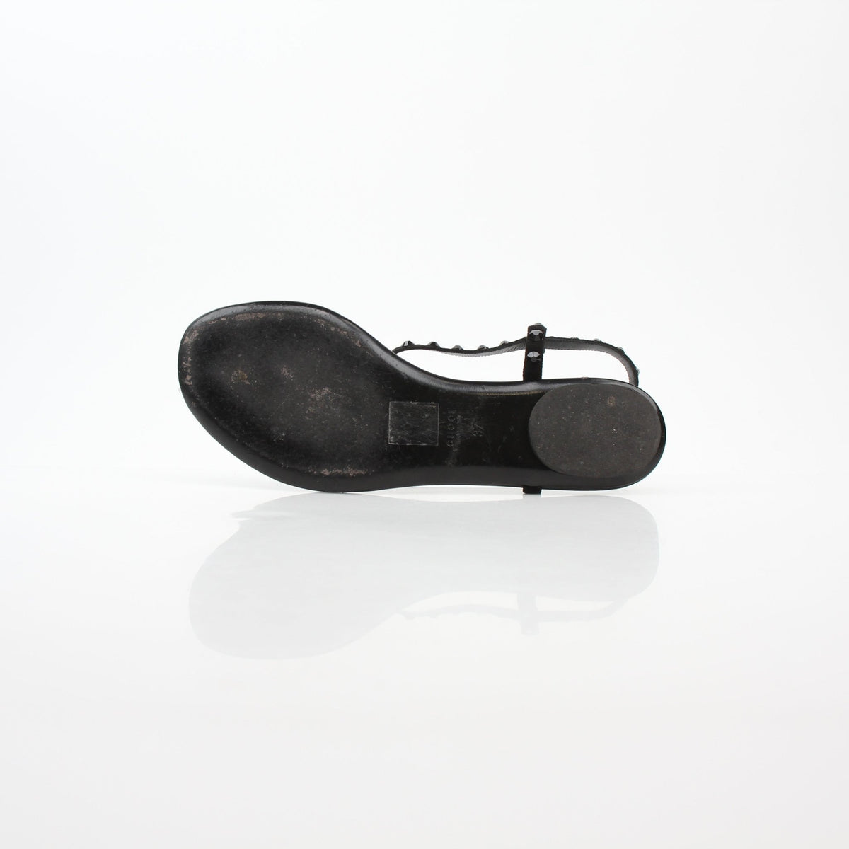 Gucci black crystal-embellished T-strap flat sandals showing crystal details and T-strap design on black leather shoes.