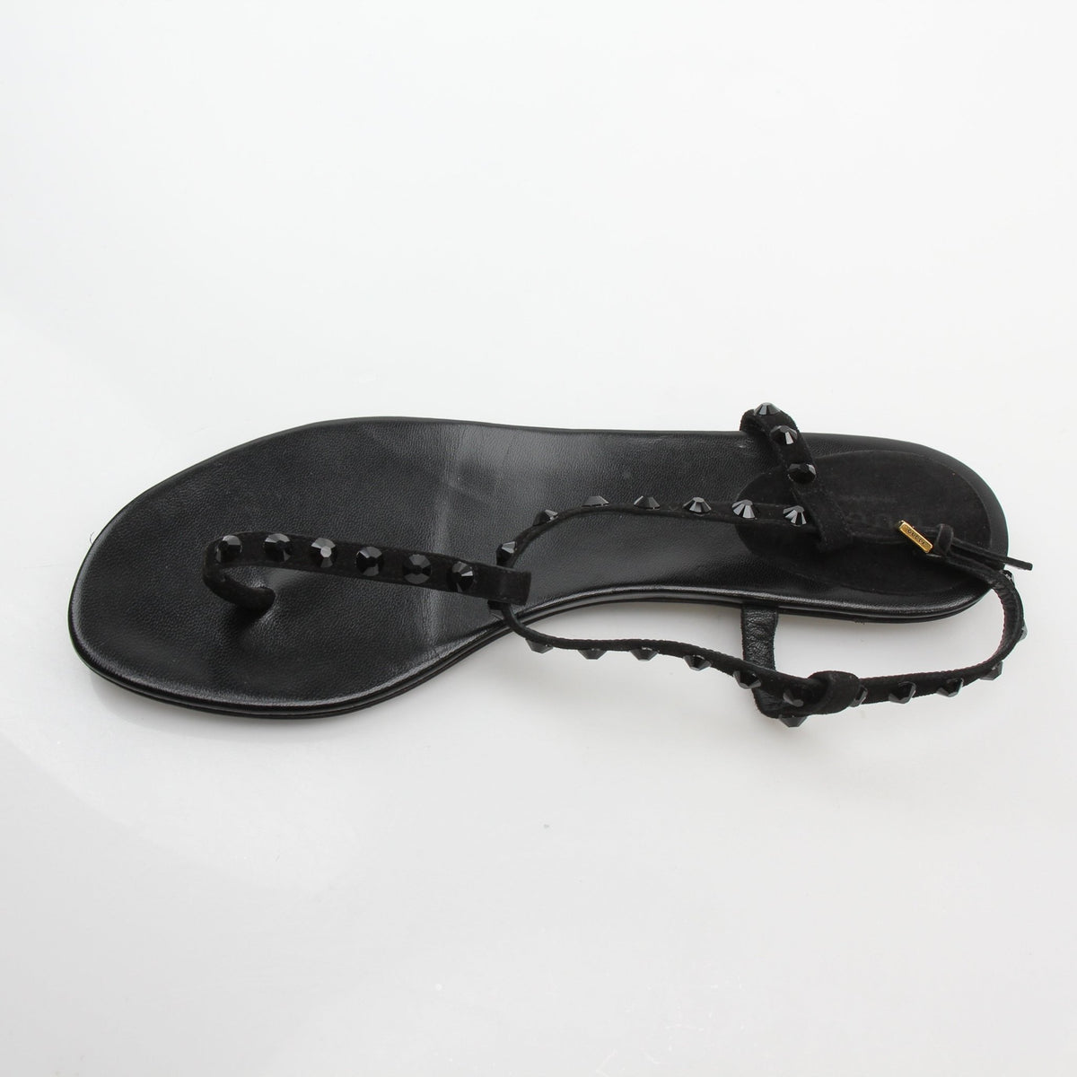 Gucci black crystal-embellished T-strap flat sandals with open toes and ankle straps, showcasing elegant footwear design.