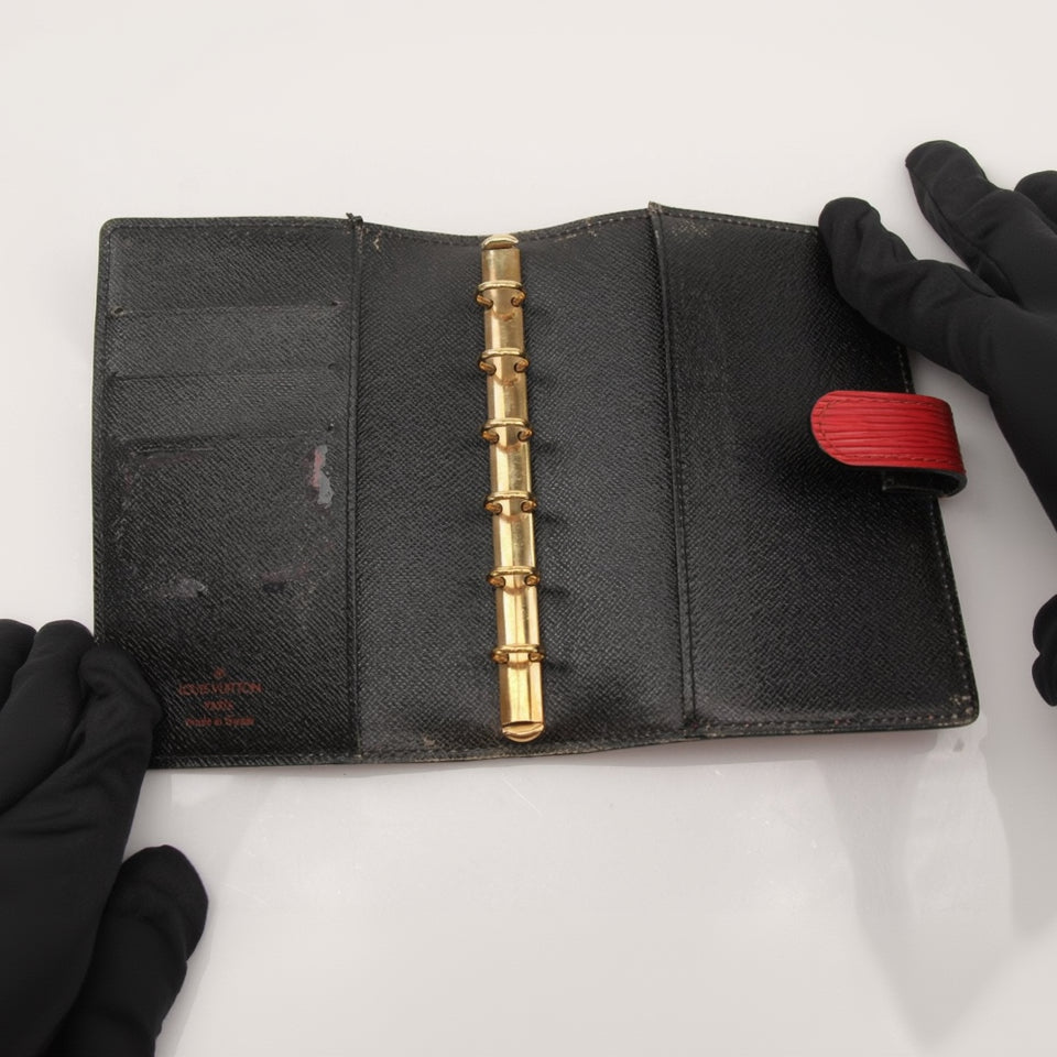 Louis Vuitton Epi Agenda Planner accessory with textured leather cover and gold accents, displayed on a neutral background.