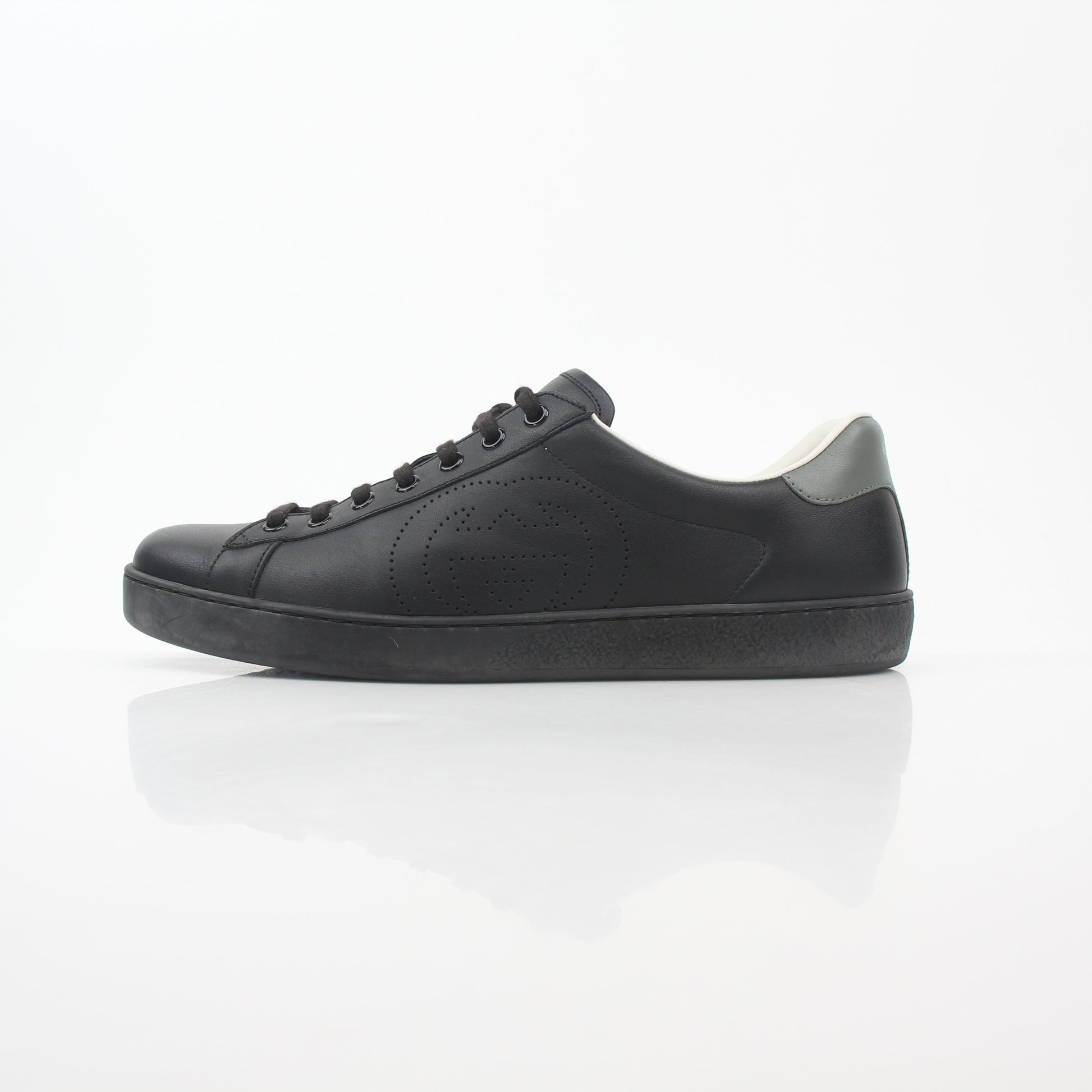 Black leather Gucci Brooklyn low-top sneakers with white soles and gold accents, displayed on a neutral background.