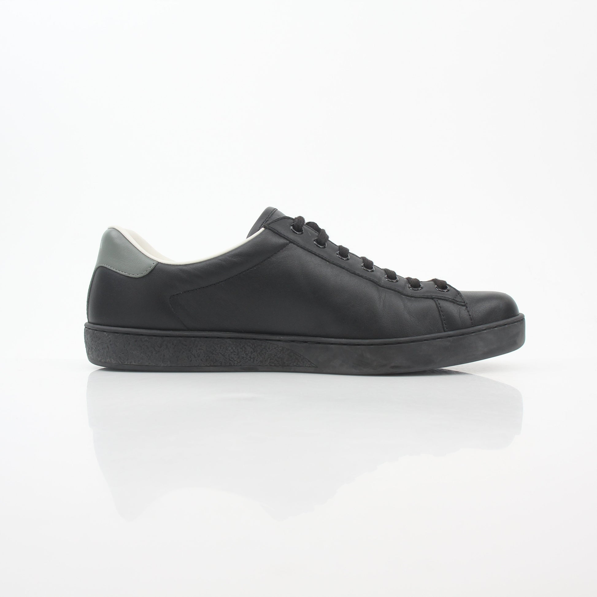 Gucci black leather Brooklyn low-top sneakers with white soles and gold accents, displayed on a white background.
