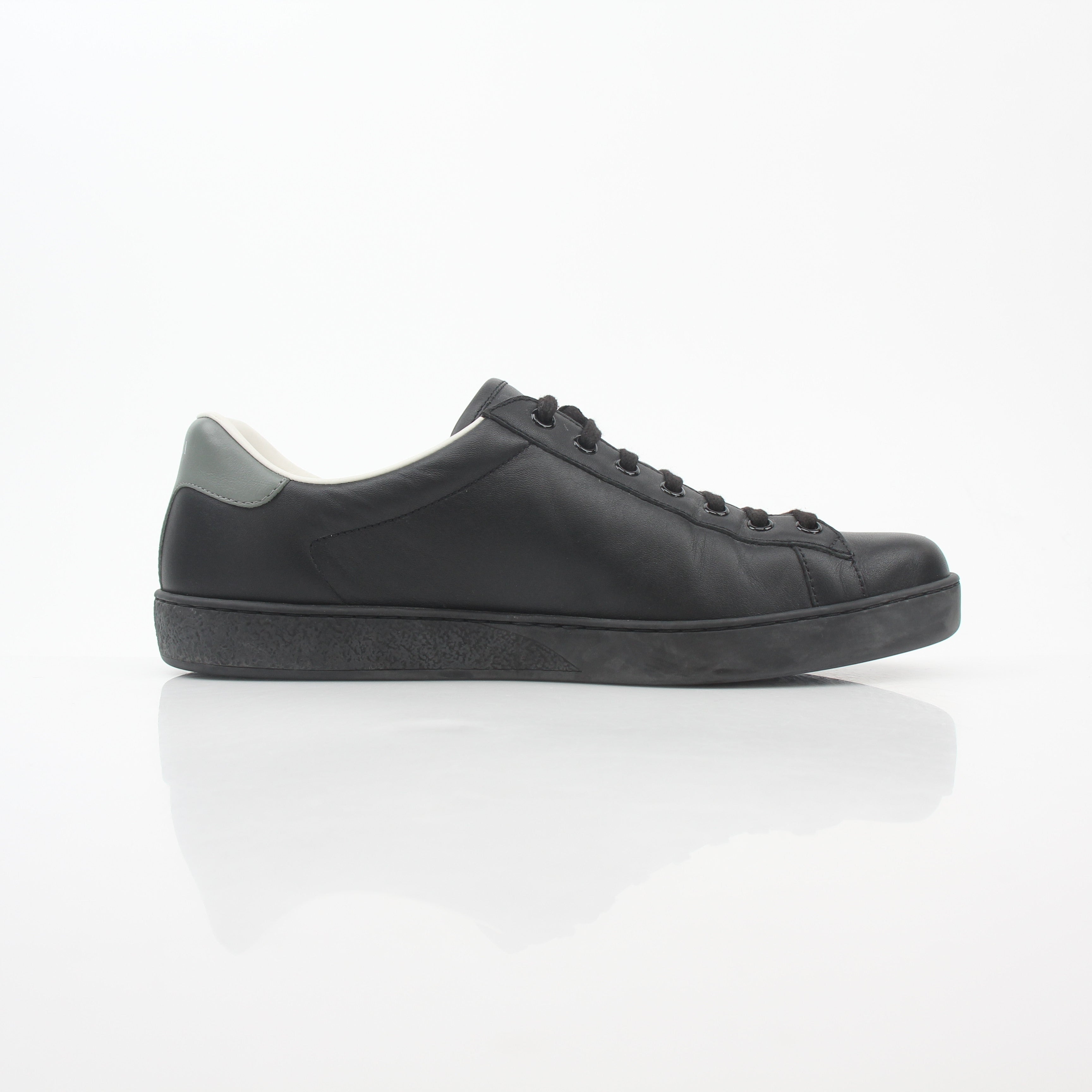 Gucci black leather Brooklyn low-top sneakers with white soles and gold accents, displayed on a white background.