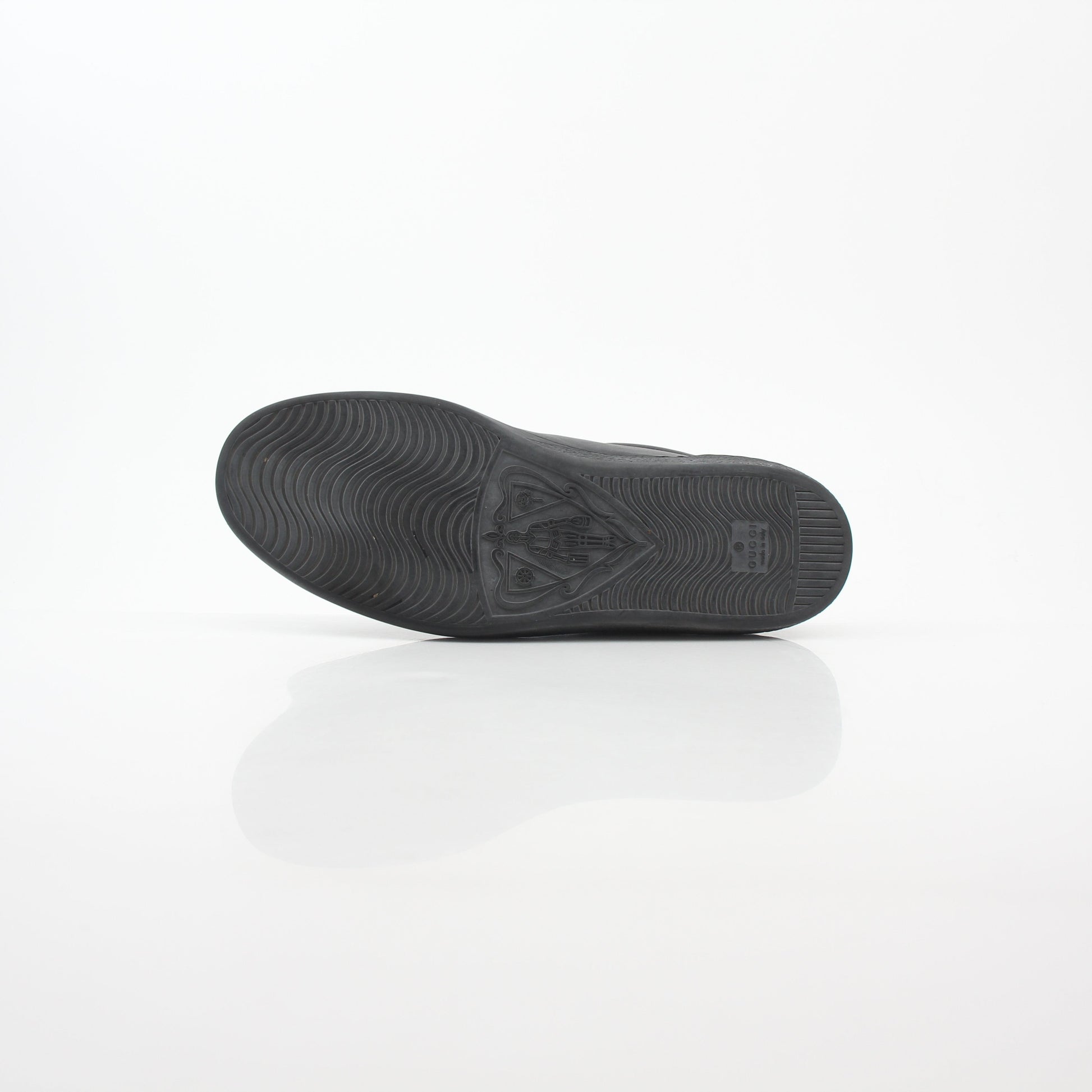 Gucci black leather Brooklyn low-top sneakers with gold accents and classic design, displayed on a plain background.