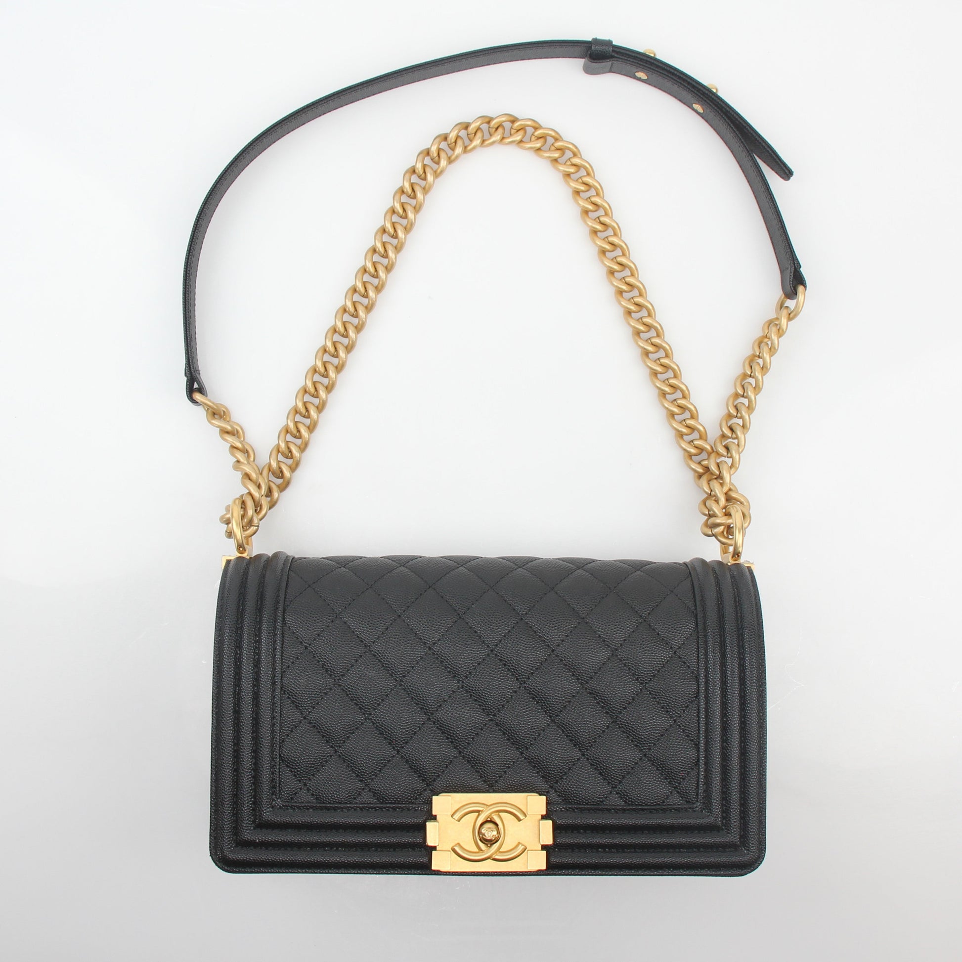 Chanel Black Caviar Boy Flap Shoulder Bag with gold hardware, featuring quilted leather and a chain strap, on a plain background.