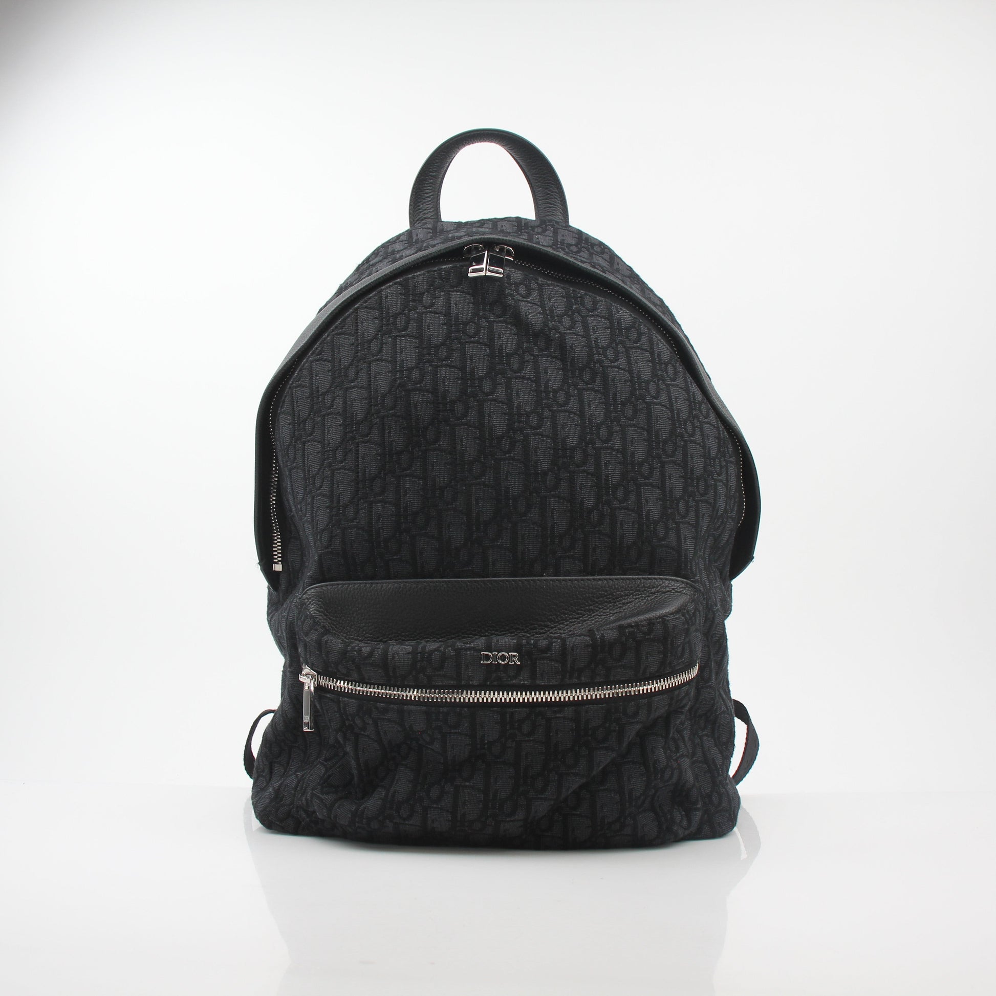 Black Christian Dior Dior Oblique Rider backpack with gold hardware, featuring adjustable straps and multiple compartments for travel.