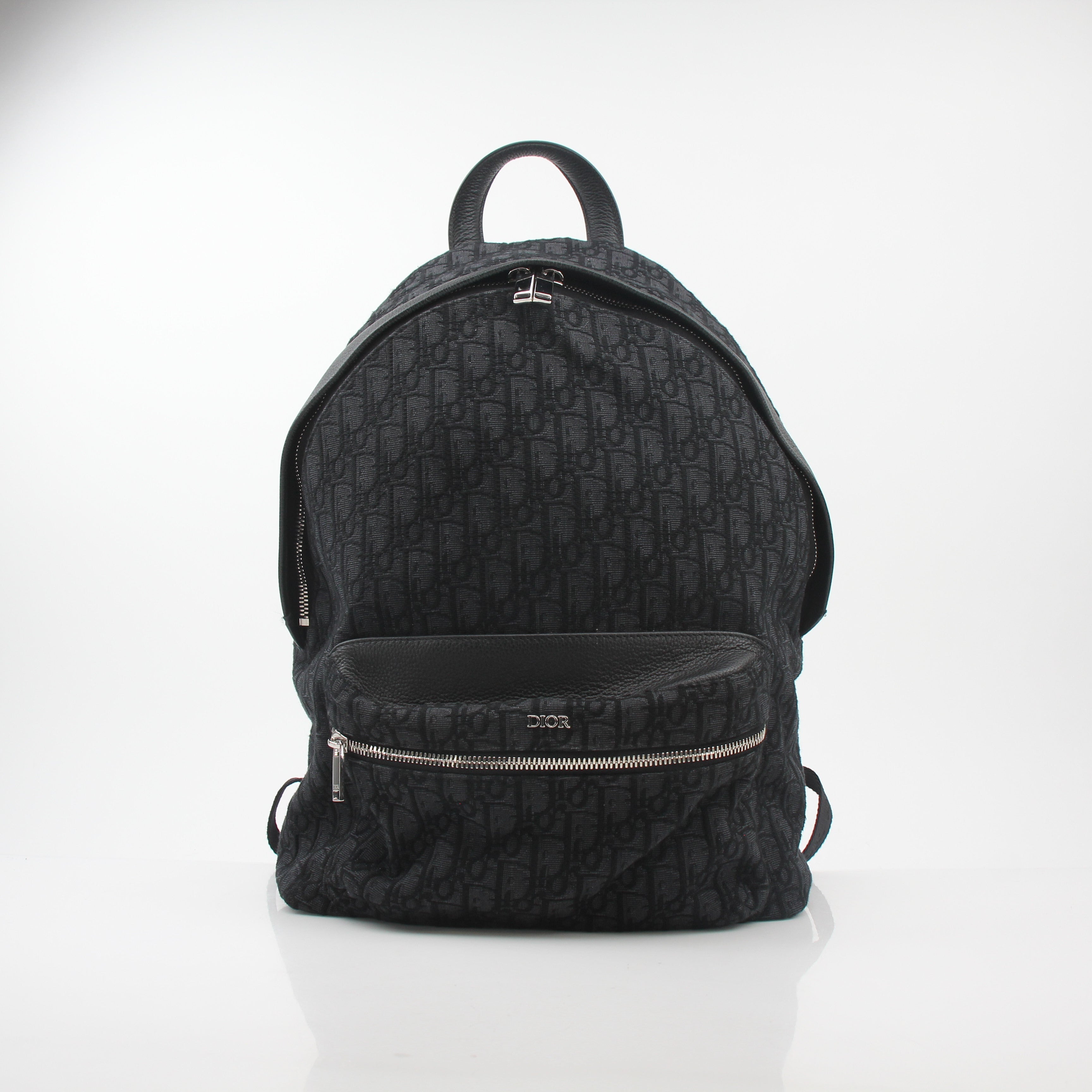 Black Christian Dior Dior Oblique Rider backpack with gold hardware, featuring adjustable straps and multiple compartments for travel.