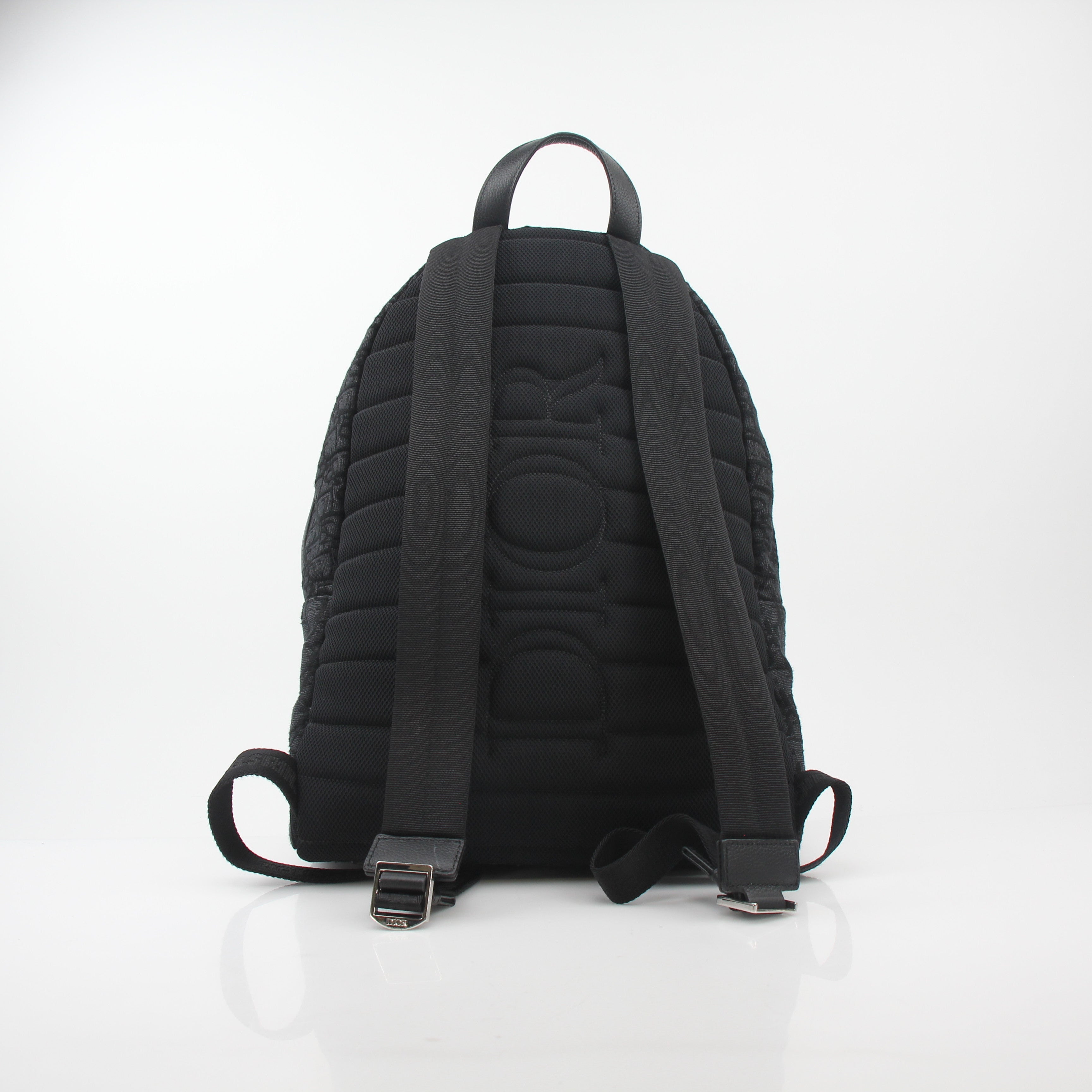 Black Christian Dior Dior Oblique Rider backpack with gold hardware, featuring adjustable straps and a spacious interior, designed for travel.