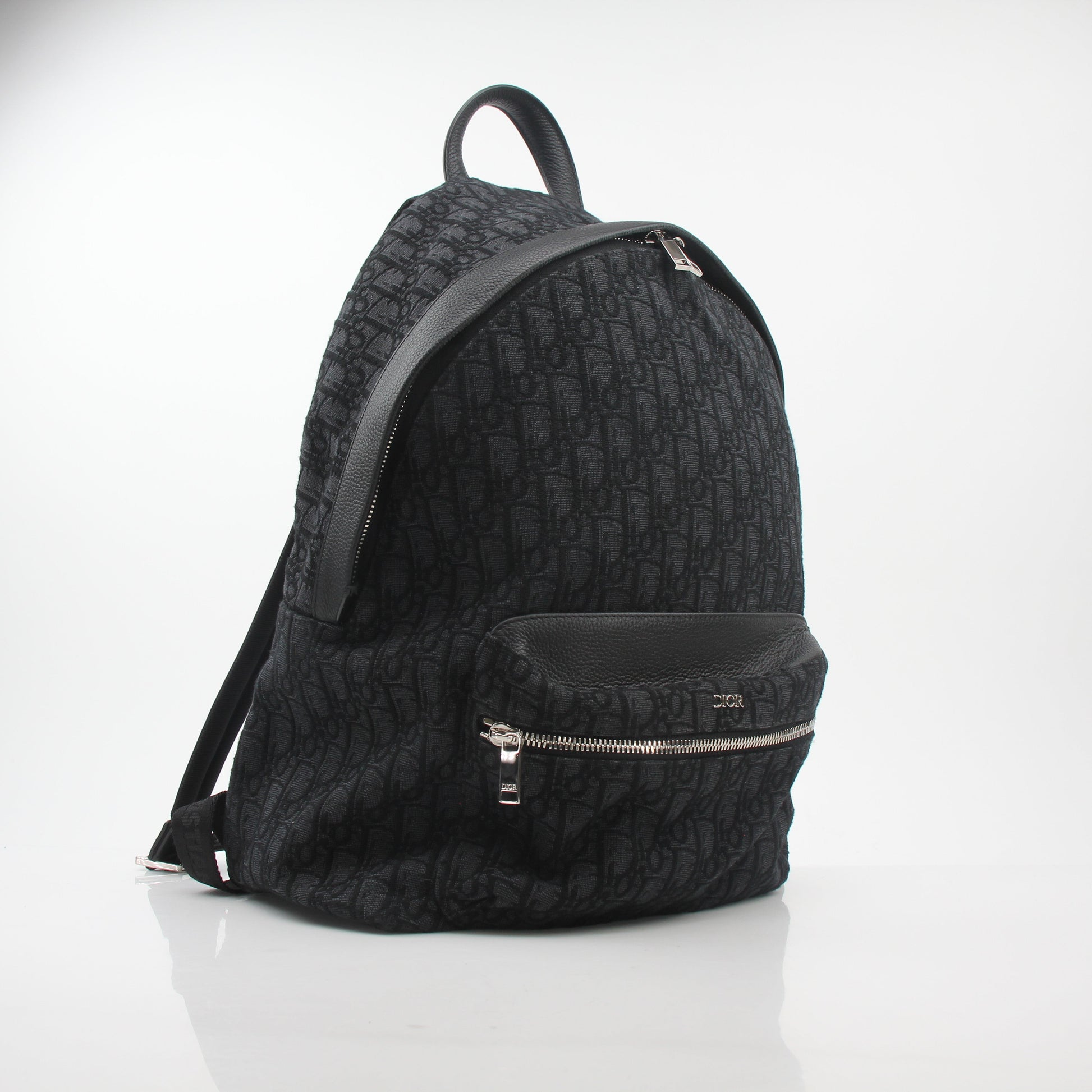 Black Dior Oblique Rider Backpack by Christian Dior, featuring logo pattern and leather accents, perfect for stylish travel and daily use.