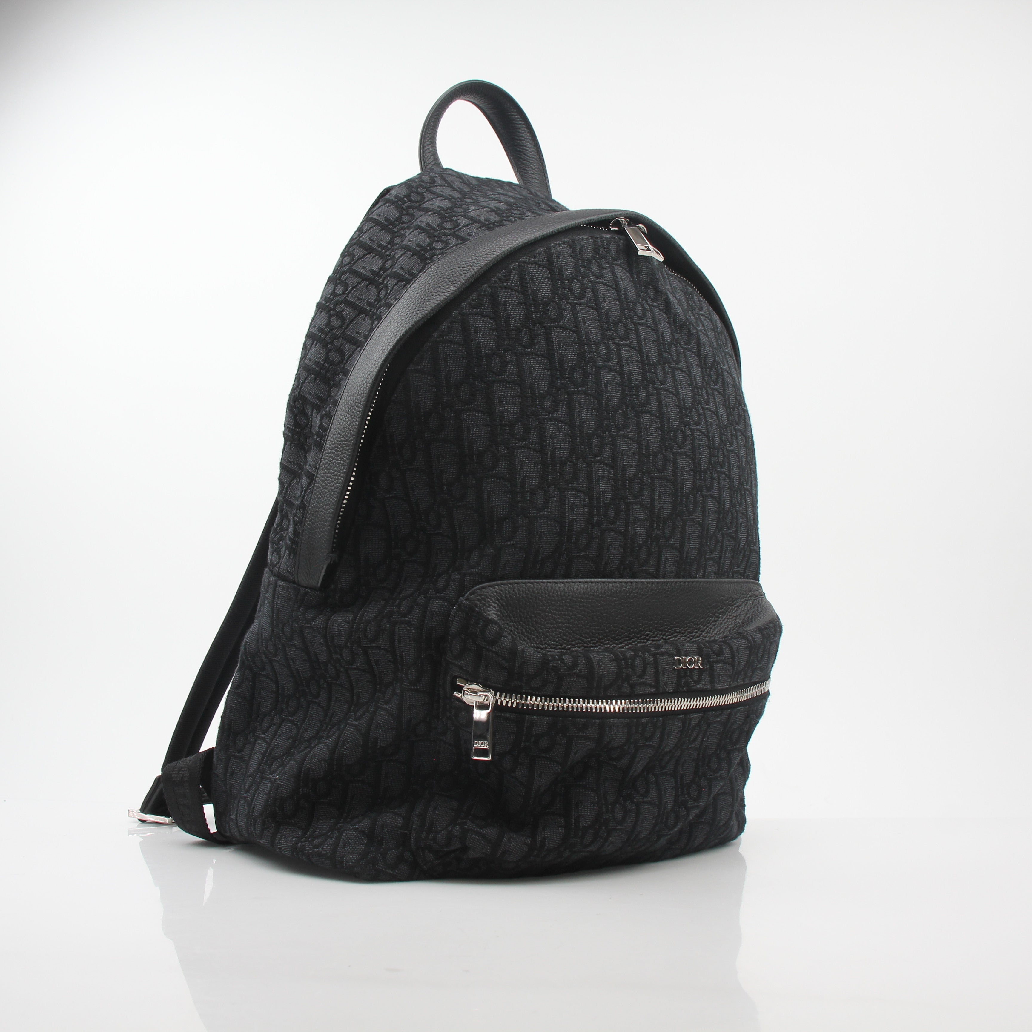 Black Dior Oblique Rider Backpack by Christian Dior, featuring logo pattern and leather accents, perfect for stylish travel and daily use.