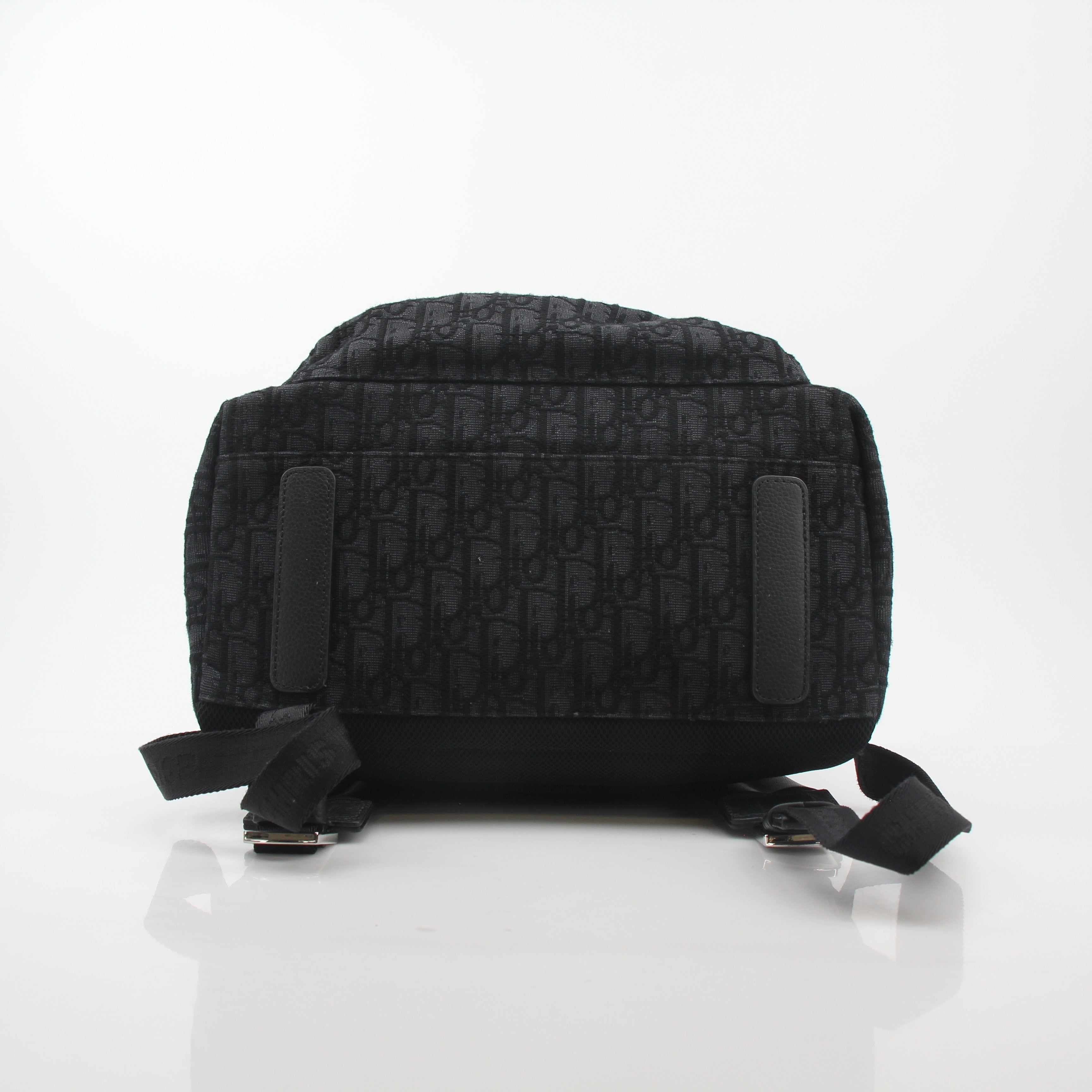 Black Dior Oblique Rider Backpack by Christian Dior, featuring sleek travel bag design with gold accents and adjustable straps.