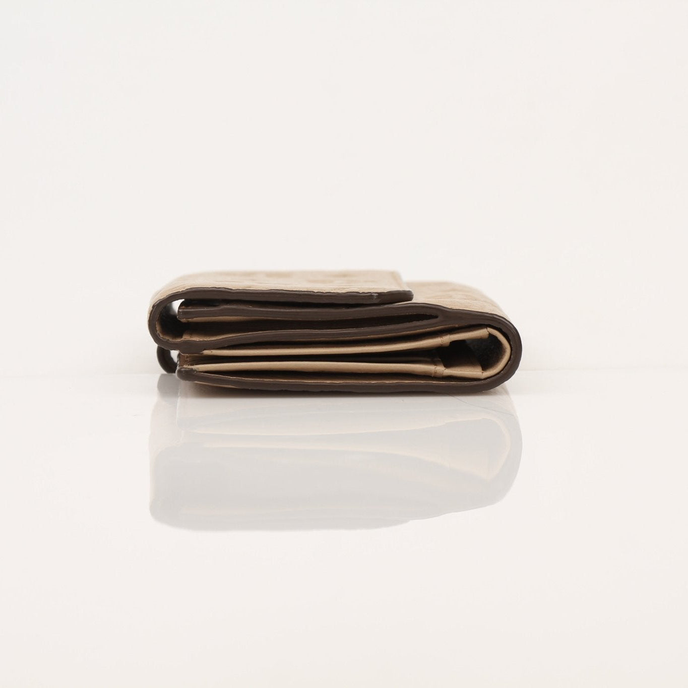 Beige MCM trifold wallet by Gold & Beyond with multiple card slots and a sleek design, displayed open showing interior compartments.