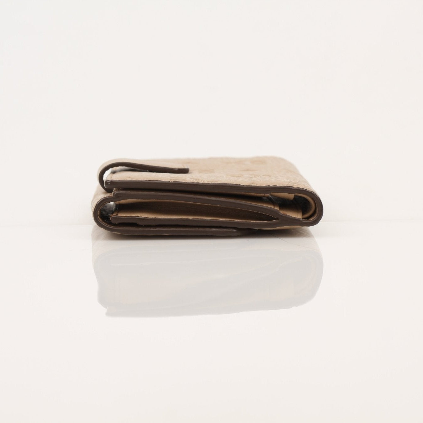 Gold & Beyond MCM beige trifold wallet with multiple card slots and a sleek design, shown open displaying interior compartments.