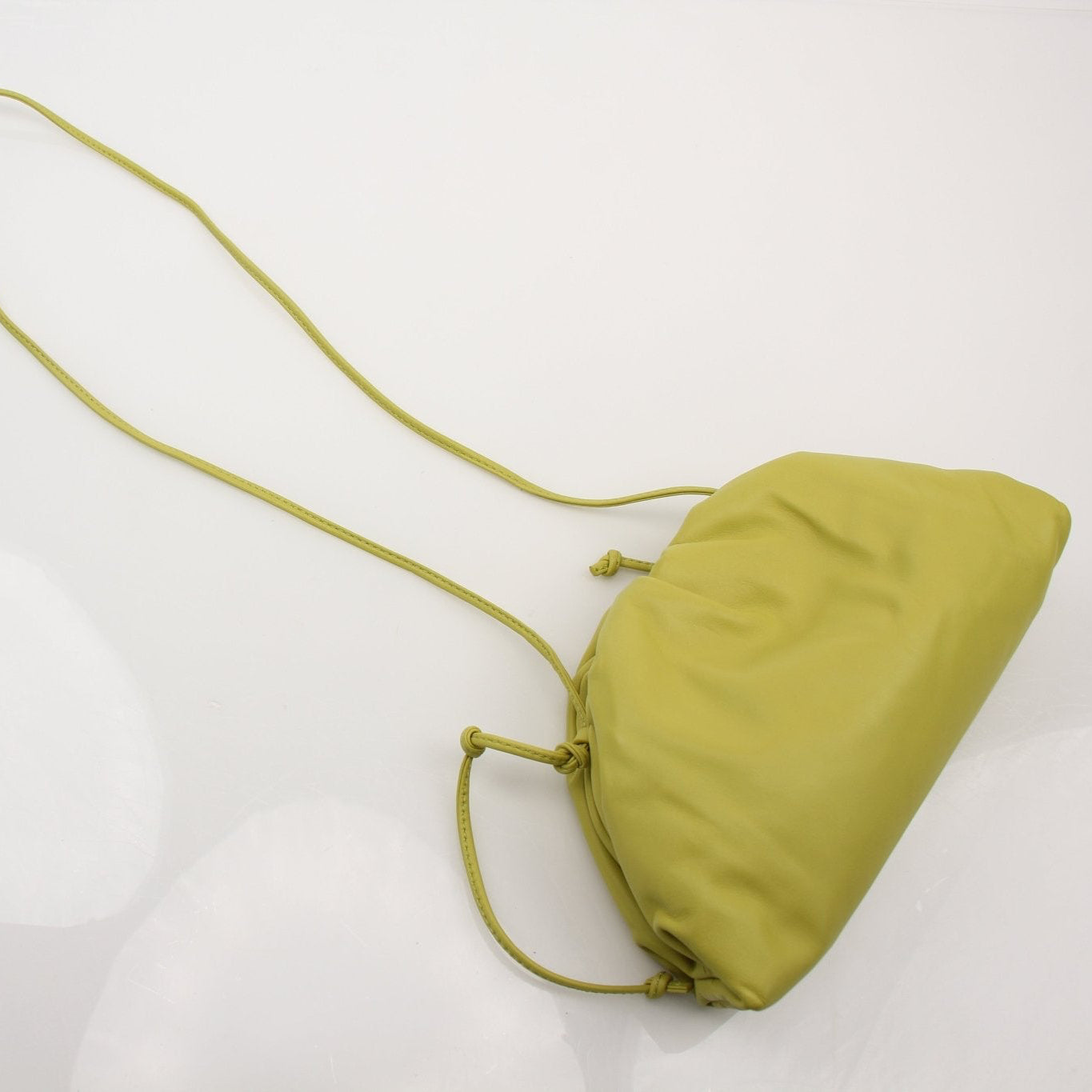 Green Bottega Veneta The Pouch Mini handbag with gold accents, shown in a close-up image highlighting its sleek design.