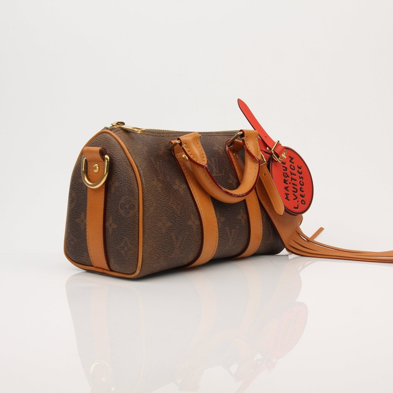 Louis Vuitton Keepall 25 Monogram Canvas Bag in gold and brown with leather trim, featuring the signature LV monogram pattern.