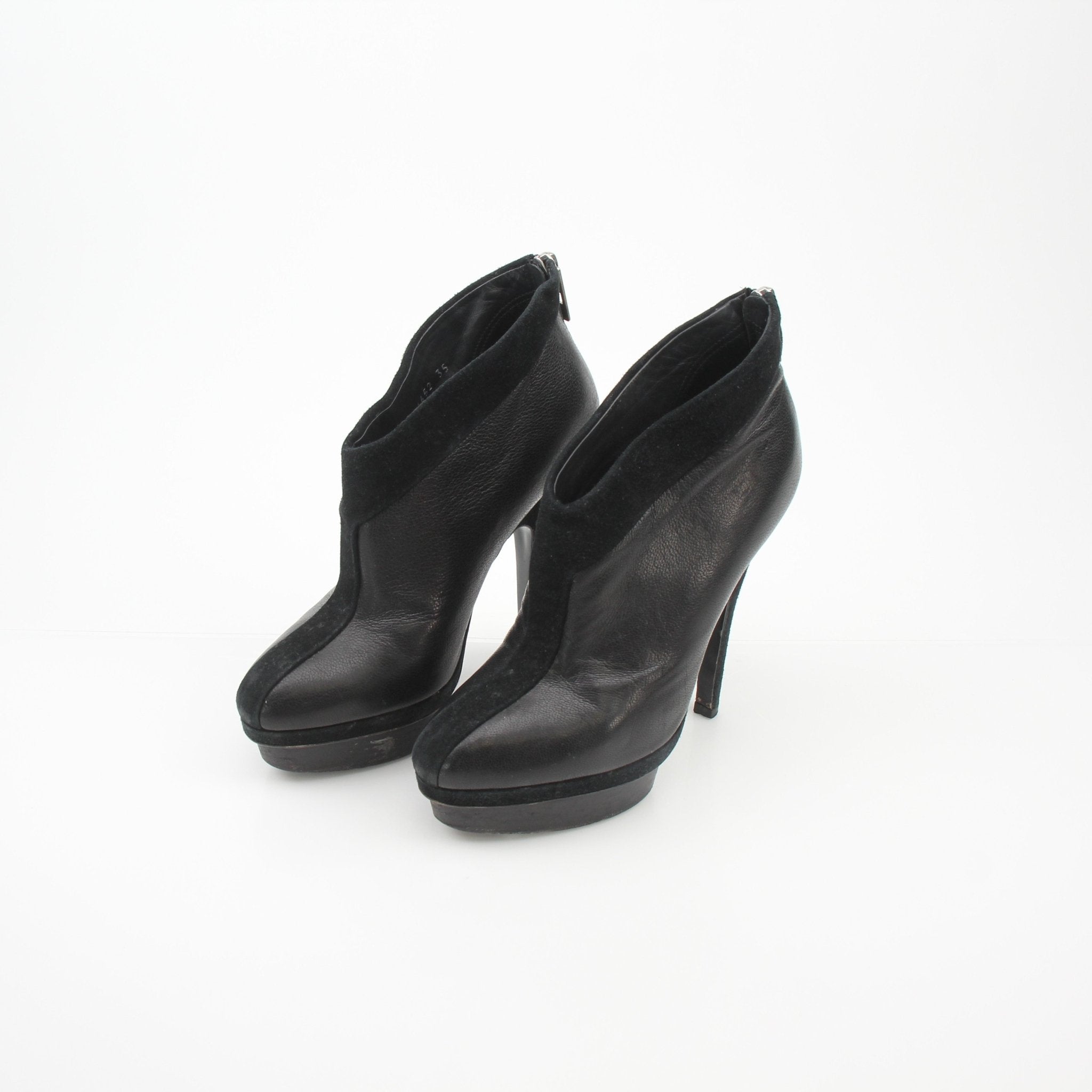 Black leather Saint Laurent Rive Gauche ankle platform pumps with high heels and sleek design, displayed on a neutral background.