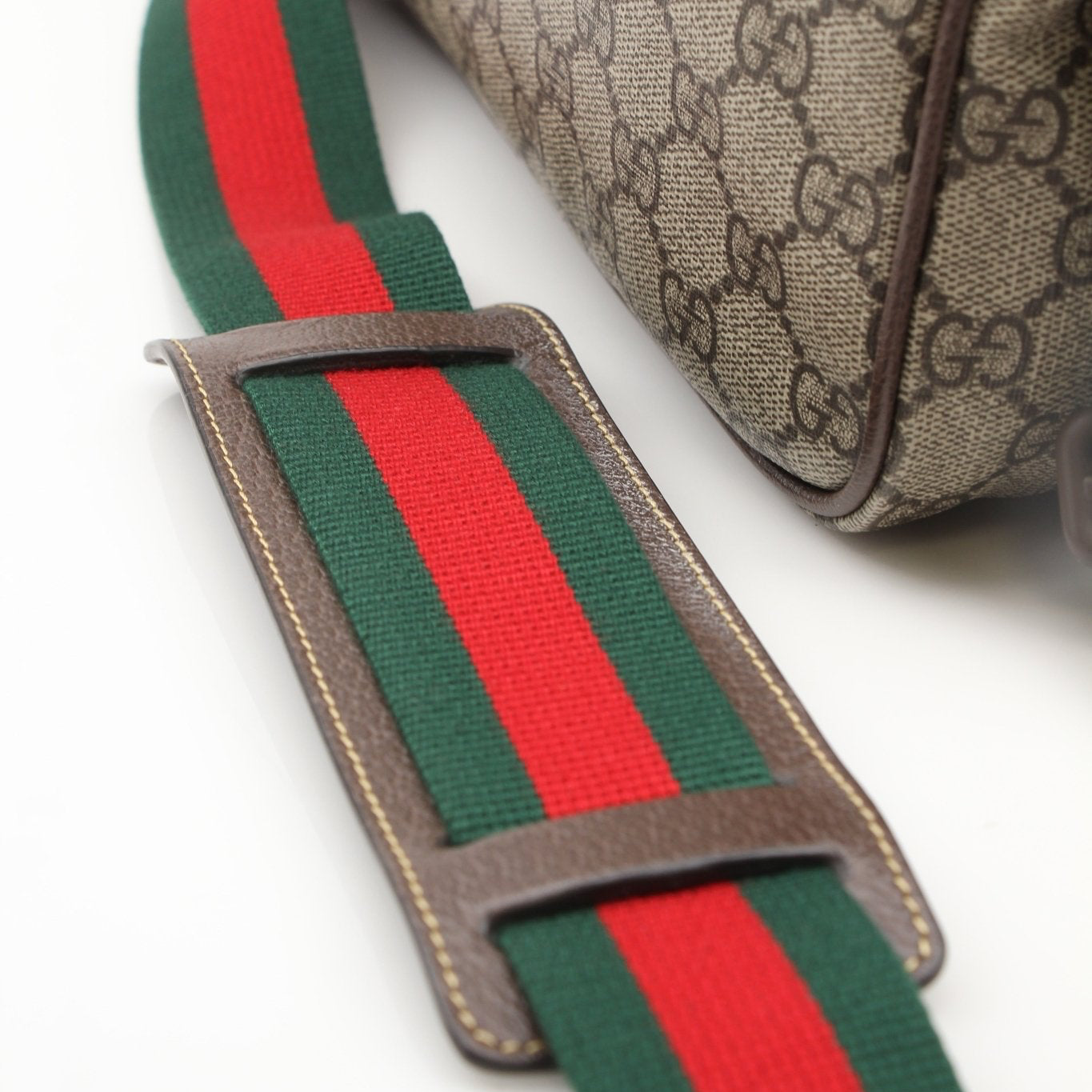 Gold & Beyond Gucci GG Supreme messenger handbag with leather strap and signature monogram pattern, stylish and functional accessory.