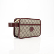 Gucci GG Supreme Dopp Kit pouch for travel, featuring signature monogram design and gold-tone hardware.