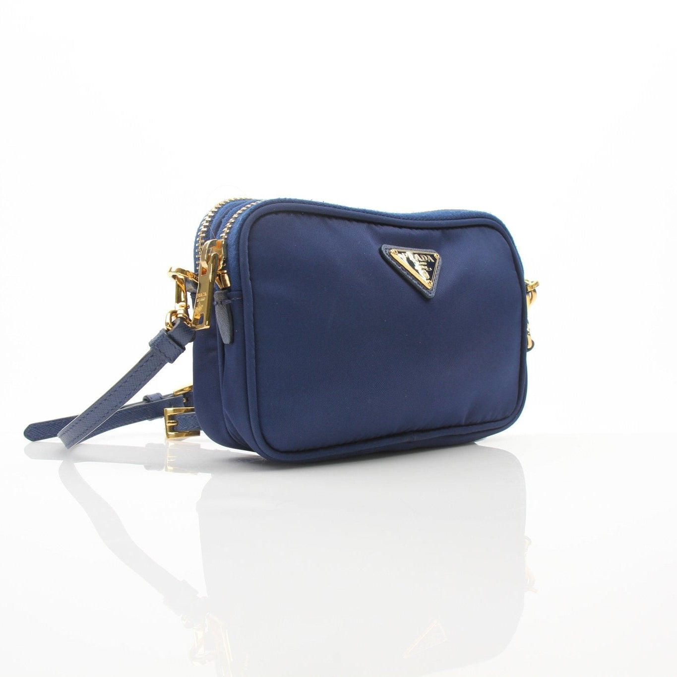Blue Prada nylon crossbody handbag with gold hardware, featuring sleek design and adjustable strap on a plain background.