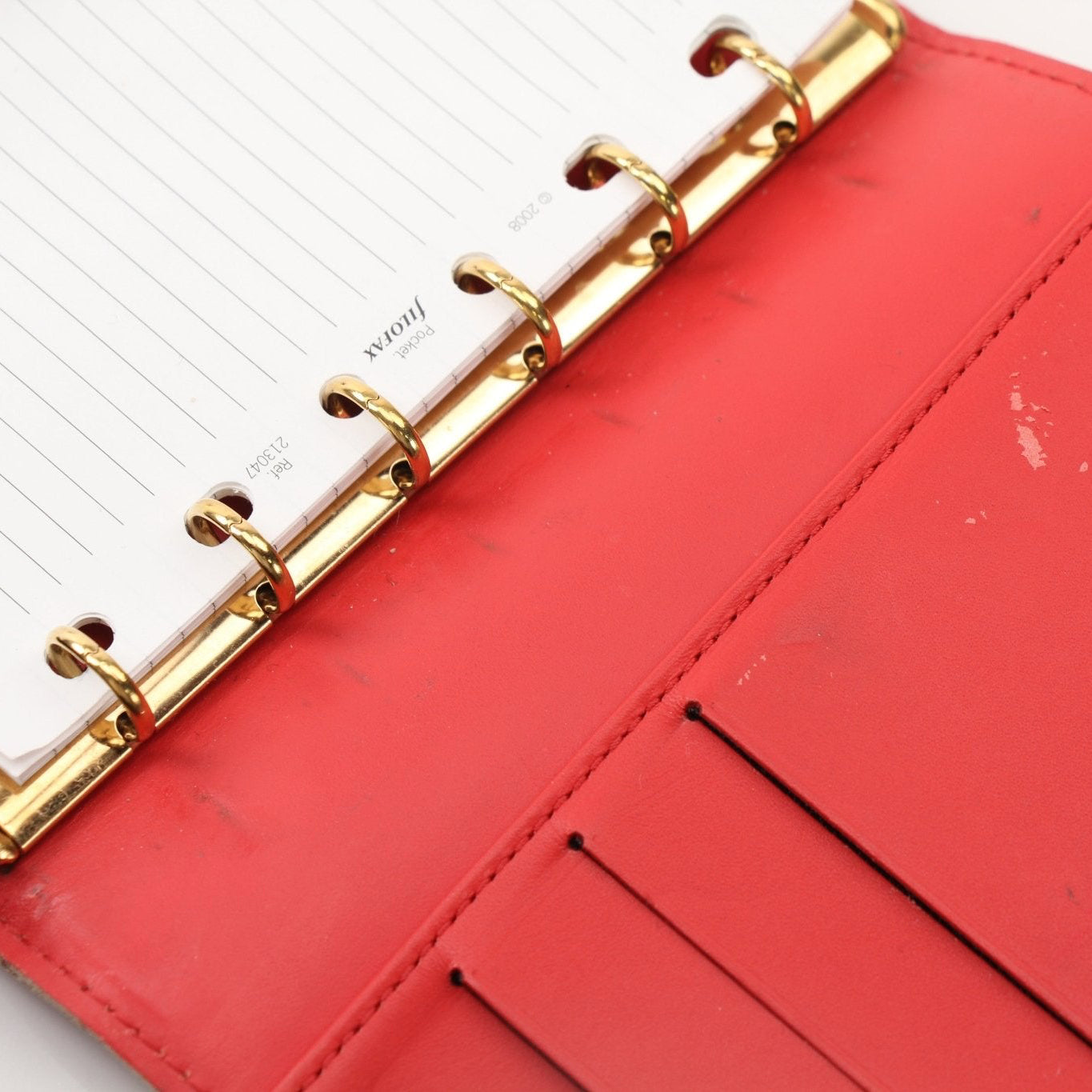 Louis Vuitton Suhali Le Fabuleux Red Agenda PM compact planner cover with gold hardware and textured leather, showcasing elegant accessory design.