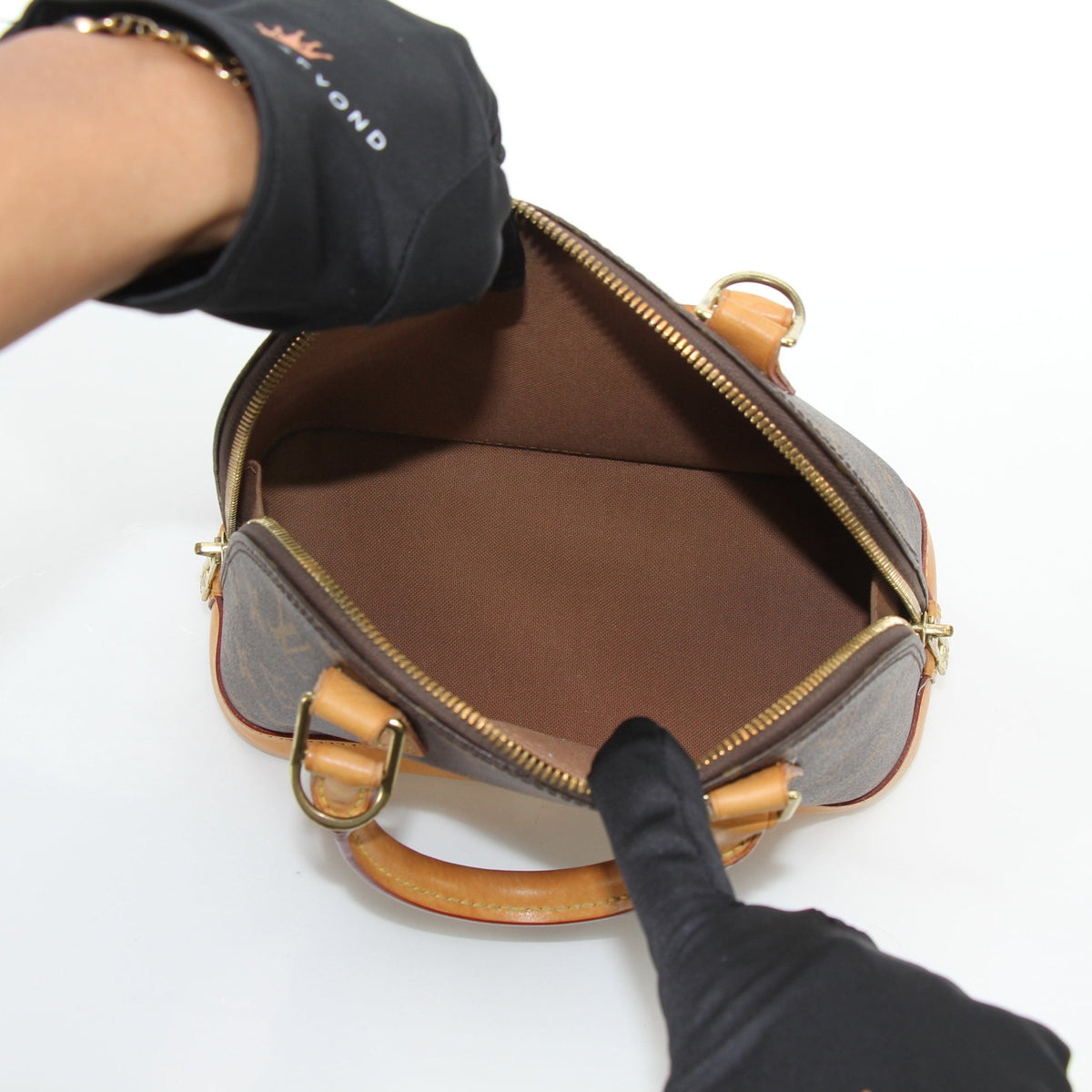 Louis Vuitton Brown Alma BB handbag with gold-tone hardware, compact stylish leather purse, photographed on a neutral background.