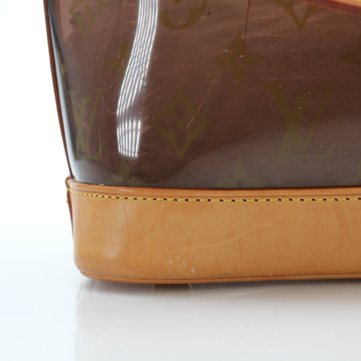 Louis Vuitton Cabas Ambre PM tote handbag with tan leather handles and gold-tone hardware, stylishly displayed against a neutral background.