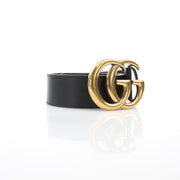 Black leather Gucci GG Marmont wide belt with gold hardware, featuring double G logo buckle and textured finish.