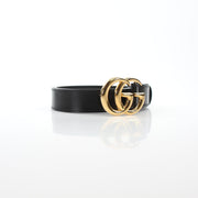 Black Gucci GG Marmont thin leather belt with gold-tone hardware, shown on a neutral background.