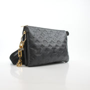 Louis Vuitton Black Coussin PM handbag with gold chain strap and textured leather, showcasing elegant design and craftsmanship.