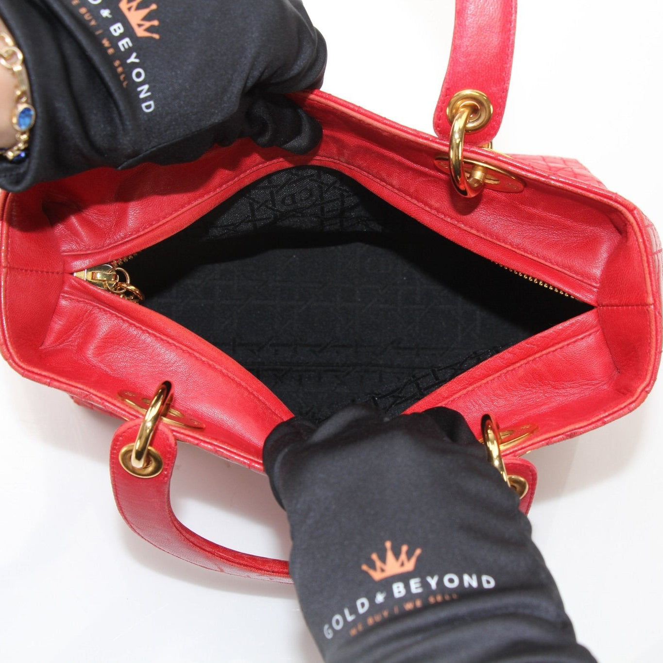 Red Christian Dior Lady Dior handbag with top handle and gold accents, displayed against a neutral background.