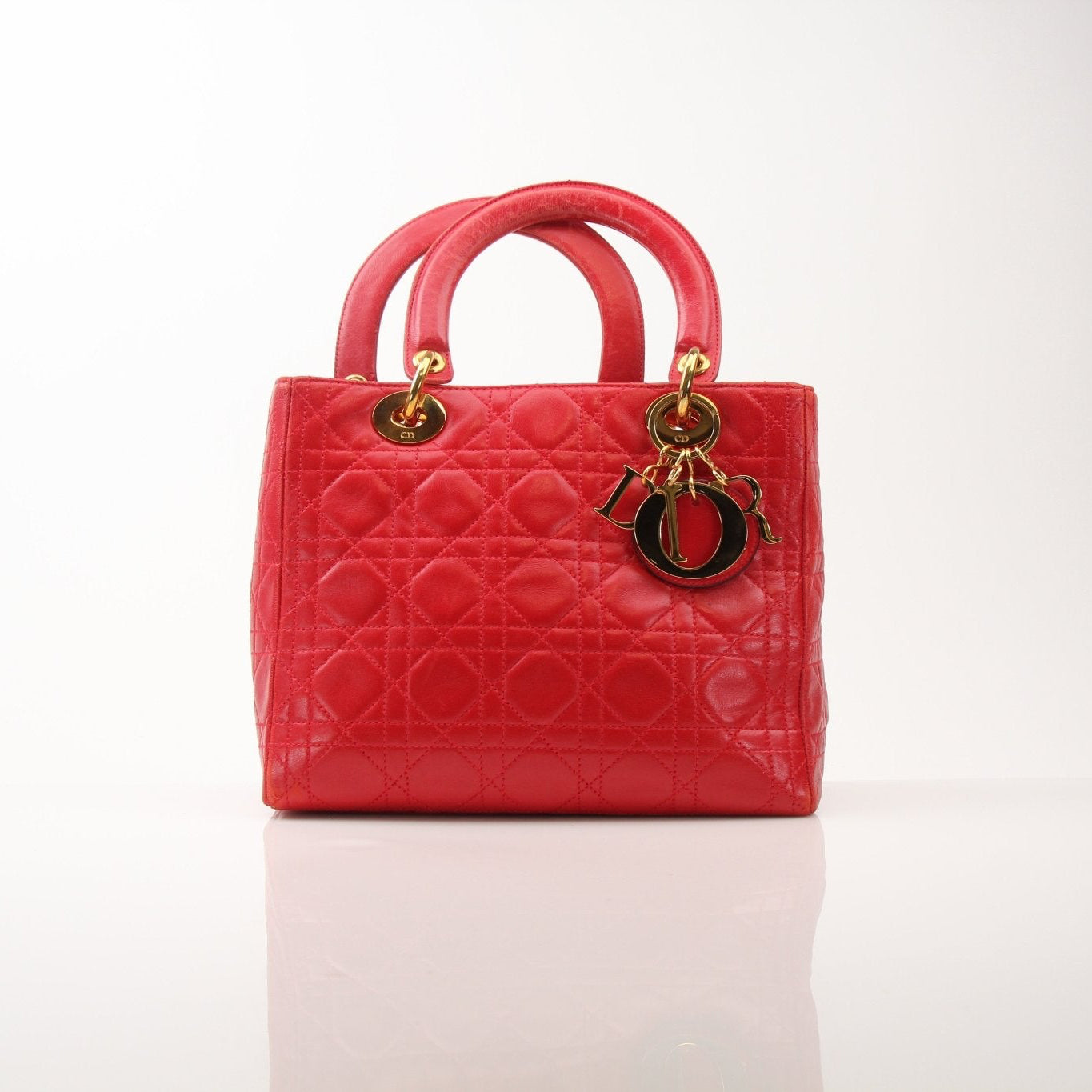 Red Christian Dior Lady Dior handbag with top handle and gold accents, featuring a classic and elegant design.