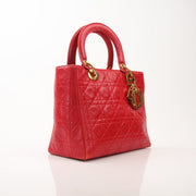 Red Lady Dior handbag with top handle in smooth leather, featuring gold hardware and signature Dior logo details.