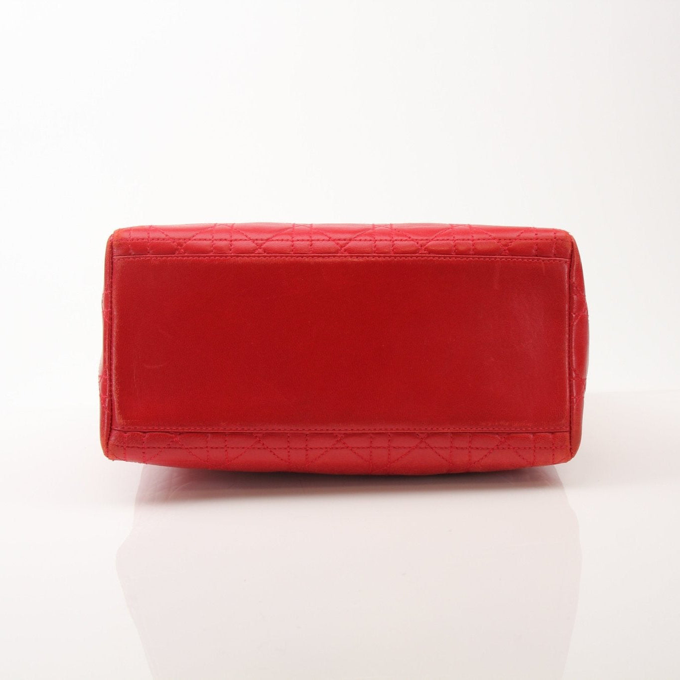 Red Christian Dior Lady Dior handbag with top handle, featuring gold accents and elegant design, displayed on a neutral background.